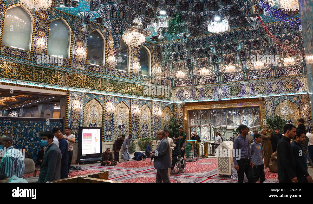 Besucher beten und reflektieren im reich verzierten Schrein von Karbalas, der von lebhaften Dekorationen und tiefer spiritueller Hingabe geprägt ist. Stockfoto