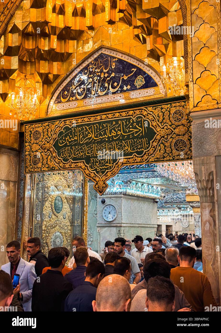 Menschenmassen versammeln sich im Imam Hussein-Schrein, der von goldenen Dekorationen beleuchtet wird, die spirituelle Hingabe und kulturelle Bedeutung widerspiegeln. Stockfoto