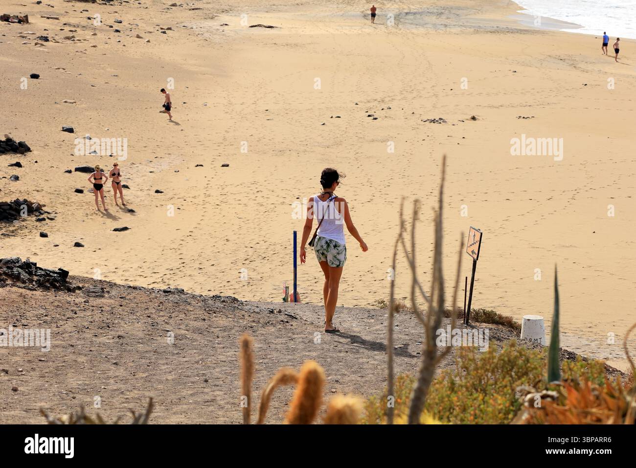 Frau, die einen Weg hinuntergeht nach Piedra Playa, El Cotillo, Fuerteventura, Kanarischen Inseln, Spanien, Europa, EU . Aufgenommen 2025 Stockfoto