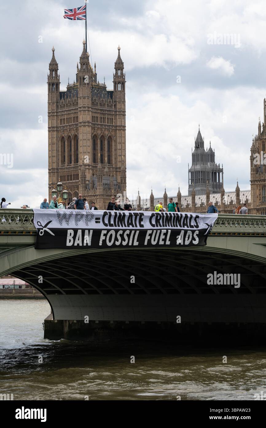 London, Großbritannien. 7. Juli 2025. Klimaaktivisten lassen ein Banner von der Westminster Bridge fallen, mit den Houses of Parliament im Hintergrund, vor einer Debatte der Abgeordneten über eine Petition zum Verbot von Werbung und Sponsoring für fossile Brennstoffe. Die Petition, die vom Naturforscher, Fernsehmoderator und Autor Chris Packham aufgeworfen wurde, erhielt über 100.000 Unterschriften und sagt, dass der fortgesetzte Verbrauch fossiler Brennstoffe mehr Menschen töten wird als das Rauchen, für das 2002 Werbung verboten wurde. Quelle: Ron Fassbender/Alamy Live News Stockfoto
