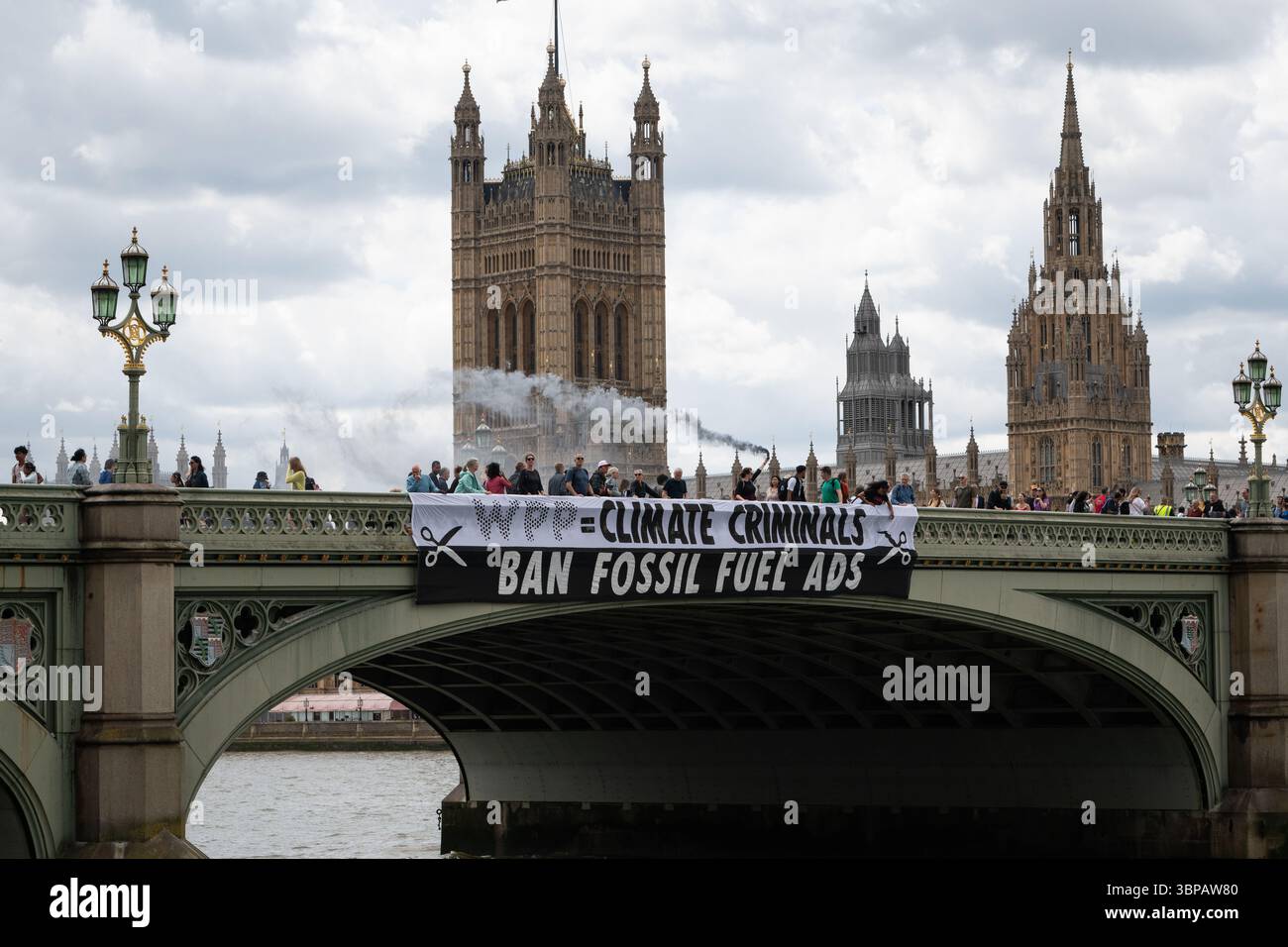 London, Großbritannien. 7. Juli 2025. Klimaaktivisten lassen ein Banner von der Westminster Bridge fallen, mit den Houses of Parliament im Hintergrund, vor einer Debatte der Abgeordneten über eine Petition zum Verbot von Werbung und Sponsoring für fossile Brennstoffe. Die Petition, die vom Naturforscher, Fernsehmoderator und Autor Chris Packham aufgeworfen wurde, erhielt über 100.000 Unterschriften und sagt, dass der fortgesetzte Verbrauch fossiler Brennstoffe mehr Menschen töten wird als das Rauchen, für das 2002 Werbung verboten wurde. Quelle: Ron Fassbender/Alamy Live News Stockfoto