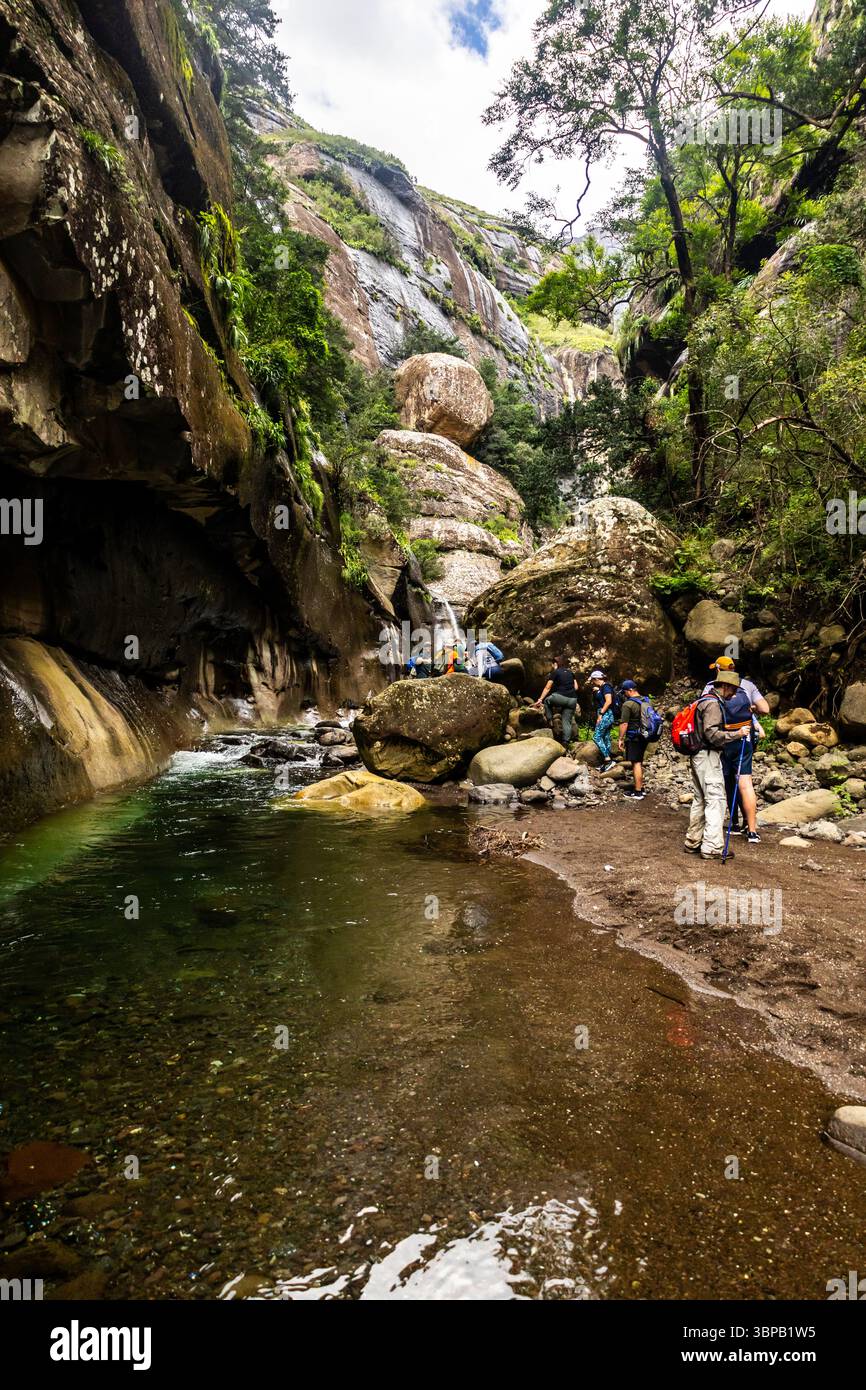 Eine Gruppe von Wanderern, die sich über Felsbrocken in der engen, aber dramatischen Tugela-Schlucht im Royal Natal-Nationalpark in den Drakensberg-Bergen bewegen Stockfoto