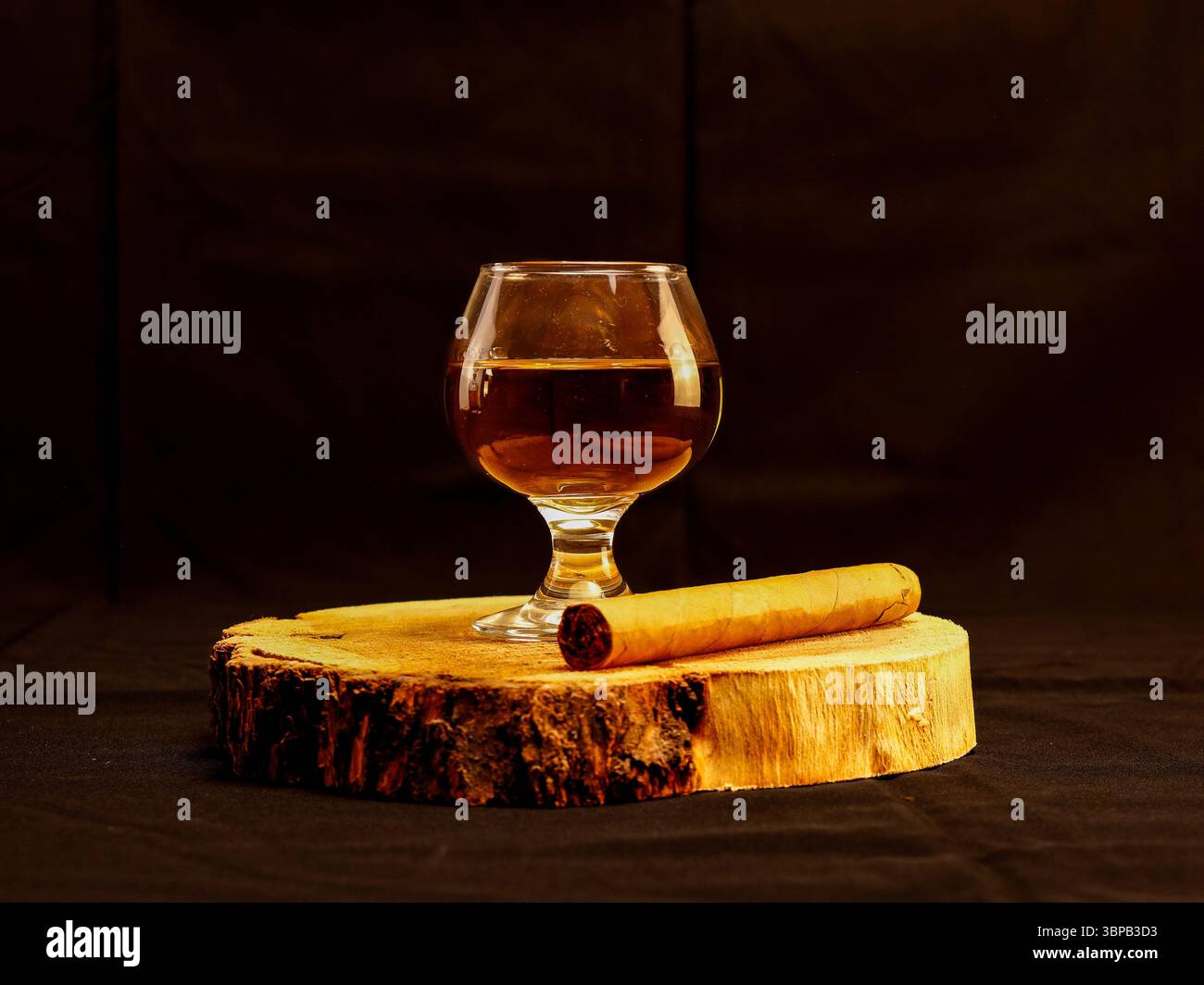 Glas Whiskey und Zigarre auf einer rustikalen Holzscheibe mit dunklem, stimmungsvollem Hintergrund. Minimalistisches und elegantes Design, perfekt für luxuriöse, maskuline Lebensfreude Stockfoto
