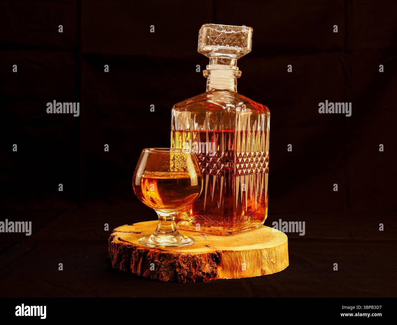 Elegante Whiskey-Dekanter und Glas auf einem Holztablett vor dunklem Hintergrund Stockfoto