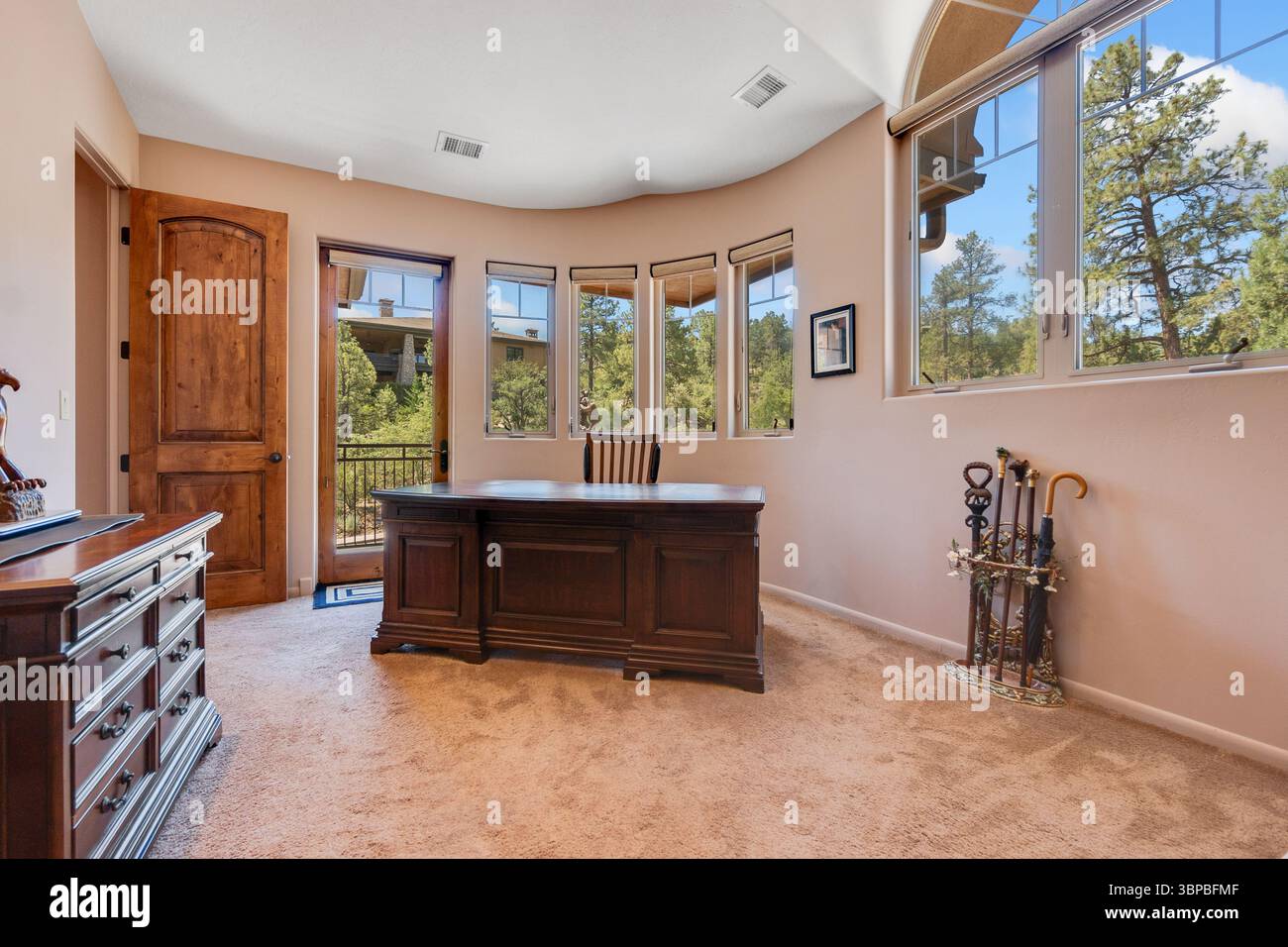 Ein geräumiger Raum mit Schreibtisch und großen Fenstern, die viel Tageslicht einlassen, schaffen eine helle Atmosphäre Stockfoto