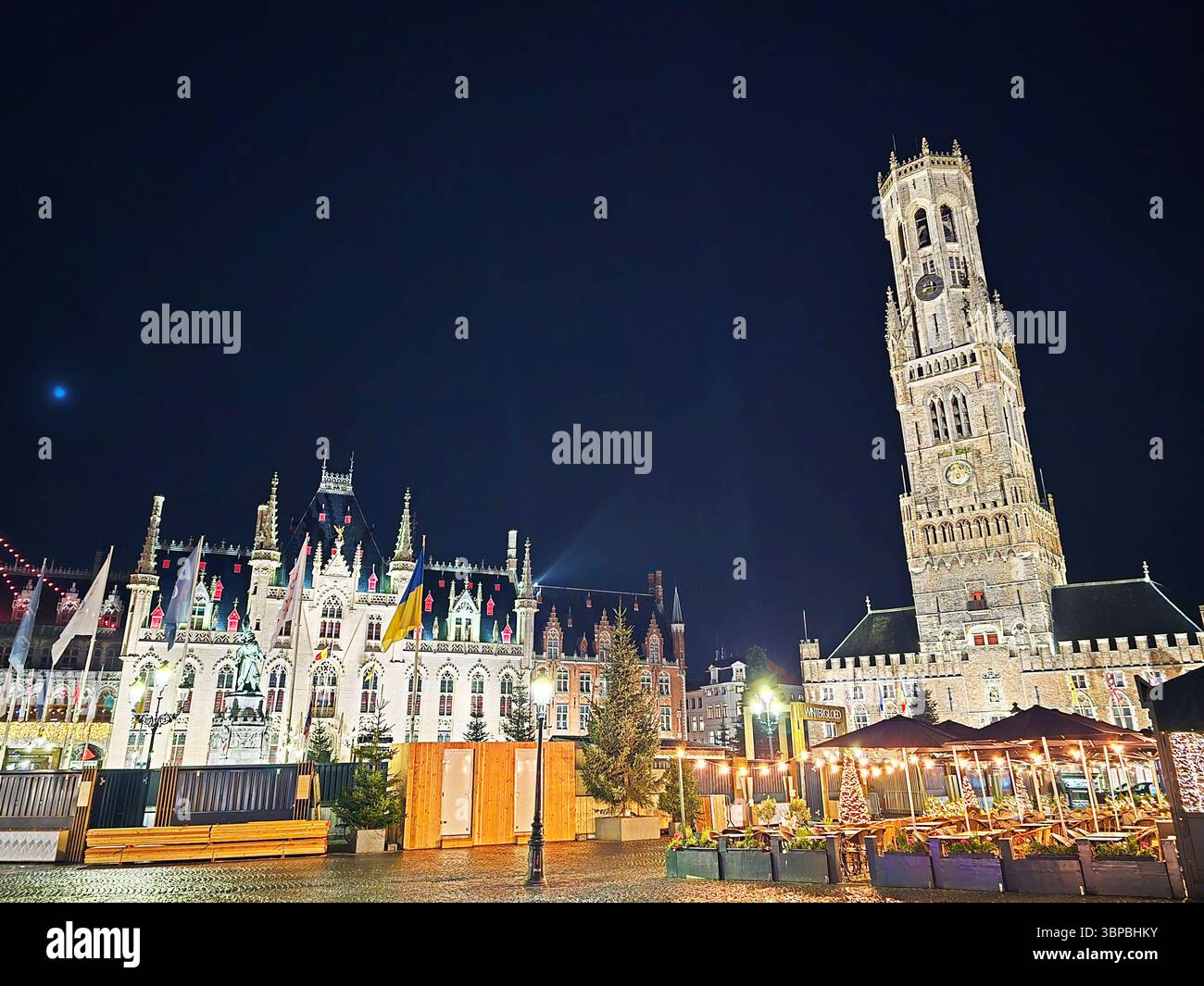 Marktplatz in Brügge, Belgien bei Nacht, mit dem Glockenturm und Weihnachtsbeleuchtung während der Weihnachtszeit. Stockfoto
