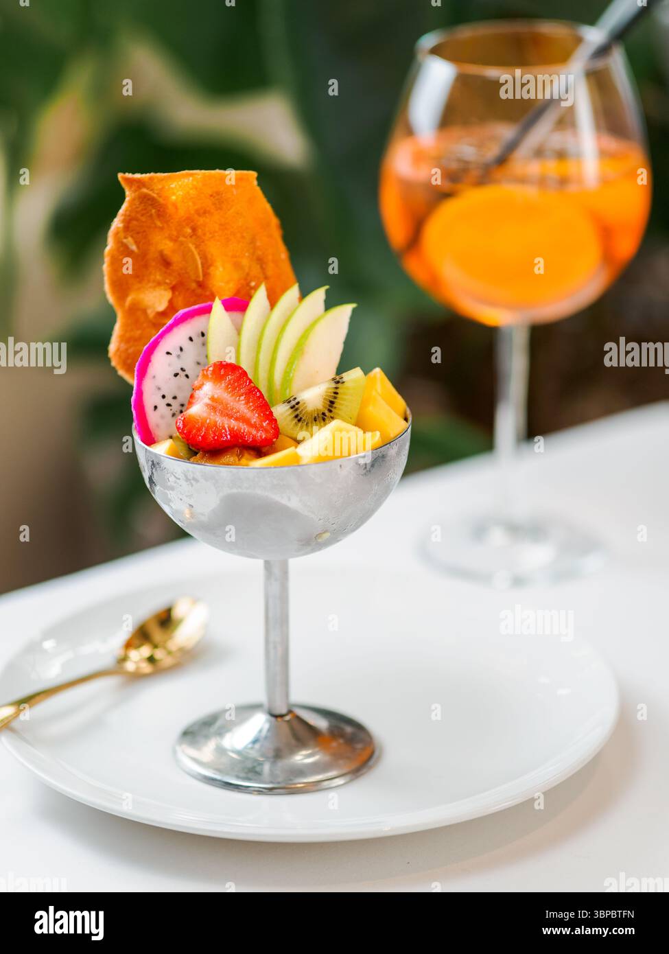 Tropical Paradise Sorbet mit Grapefruit, Mango, Passionsfrucht dekoriert mit frischem Obst und knusprigen Tuilkeksen. Tropisches Eis im Eisbecher aus Metall Stockfoto