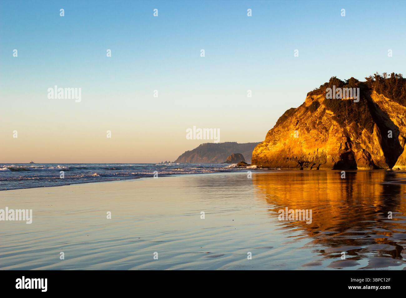 Hug Point State Park, Oregon – 28. November 2015: Wellen krachen am Strand, wenn die Sonne untergeht und ein goldenes Licht auf die Klippen werfen. Stockfoto