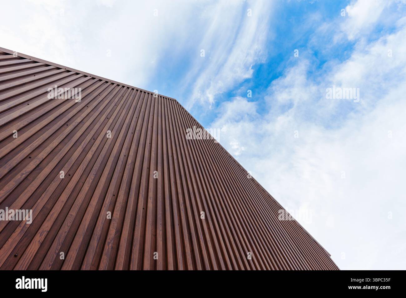 Braunes Gebäude in moderner Architektur mit vertikal beschichtetem Holzmuster, Metallstahl und geometrischem Muster unter dem Himmel Stockfoto