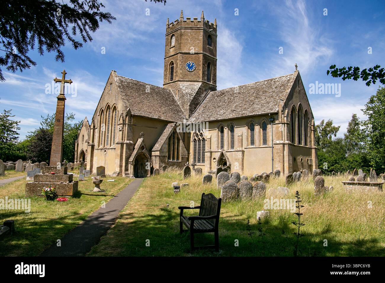 Historische Steinkirche St. Mary's in Uffington Oxfordshire mit Friedhof umgeben von grünen Bäumen unter einem klaren blauen Himmel an einem sonnigen Tag Stockfoto