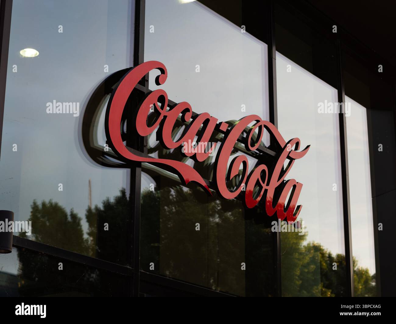 Coca Cola-Logo des Marken- und Getränkeherstellers. Das rote Logo befindet sich in einem modernen Bürogebäude. Firmensymbol an der Außenwand. Stockfoto