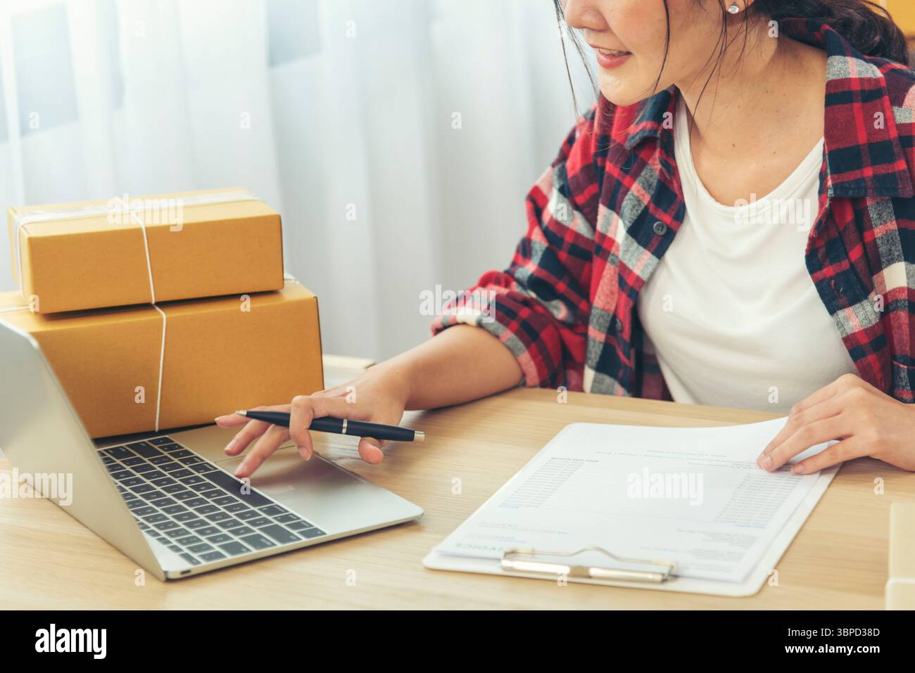 Frau, die Lagerbestand überprüft Waren Lieferung Lieferung Paket Versand Dokument Checkliste verwenden. Asiatische Frau Startup Kleinunternehmen im Home Office. Online-Unternehmer Stockfoto