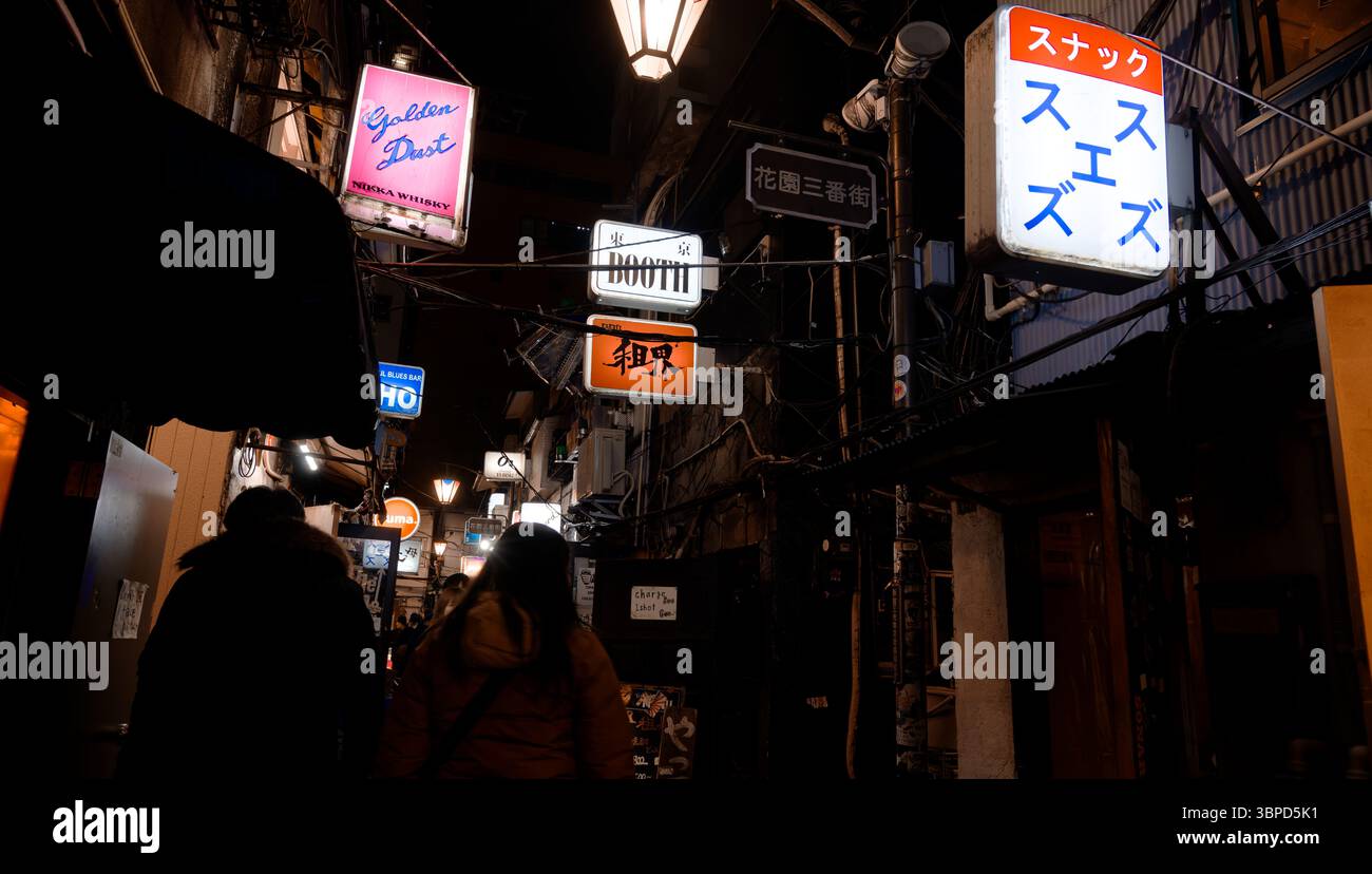 Die enge Gasse in Tokio, gesäumt von leuchtenden Barschildern, lädt Nachtschwärmer ein, die versteckten Bars zu erkunden Stockfoto