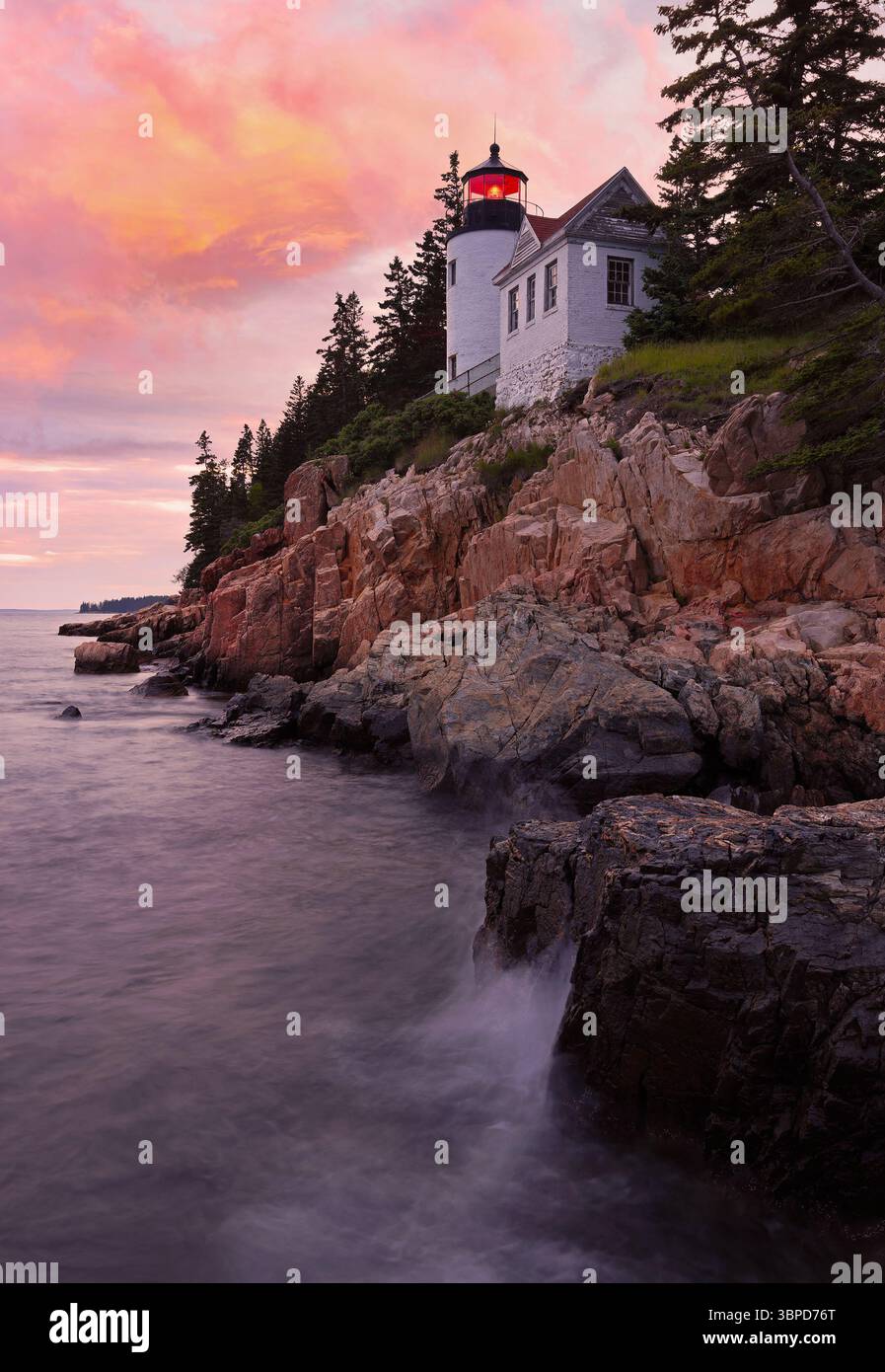 Bass Harbour Lighthouse bei Sonnenuntergang mit dramatischen Felsen und dem Atlantischen Ozean im Vordergrund, Acadia National Park, Maine, USA Stockfoto