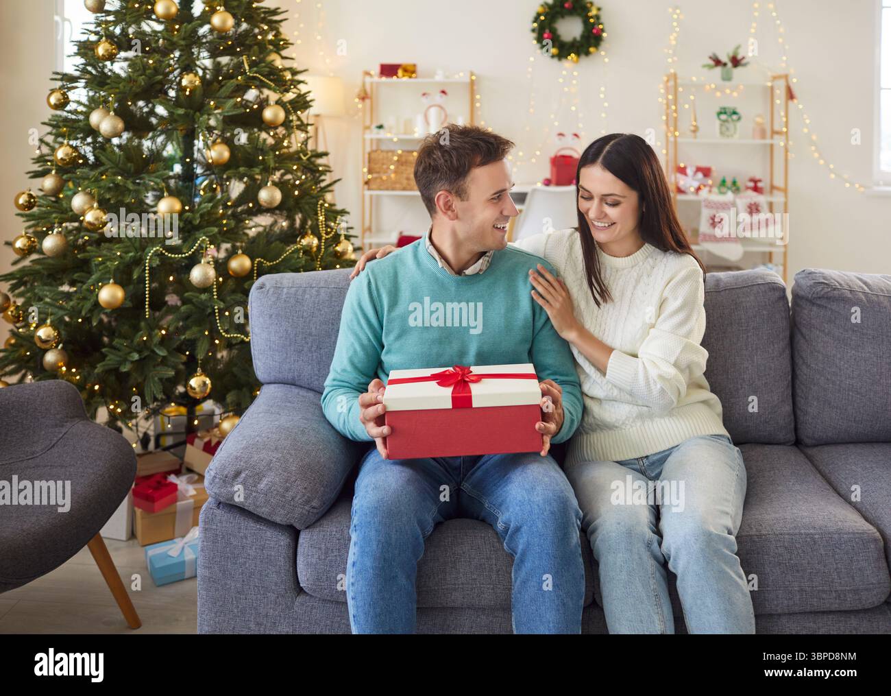 Mann, der Ein Weihnachts- oder Neujahrsgeschenk von einer Frau zu Hause eröffnet Stockfoto