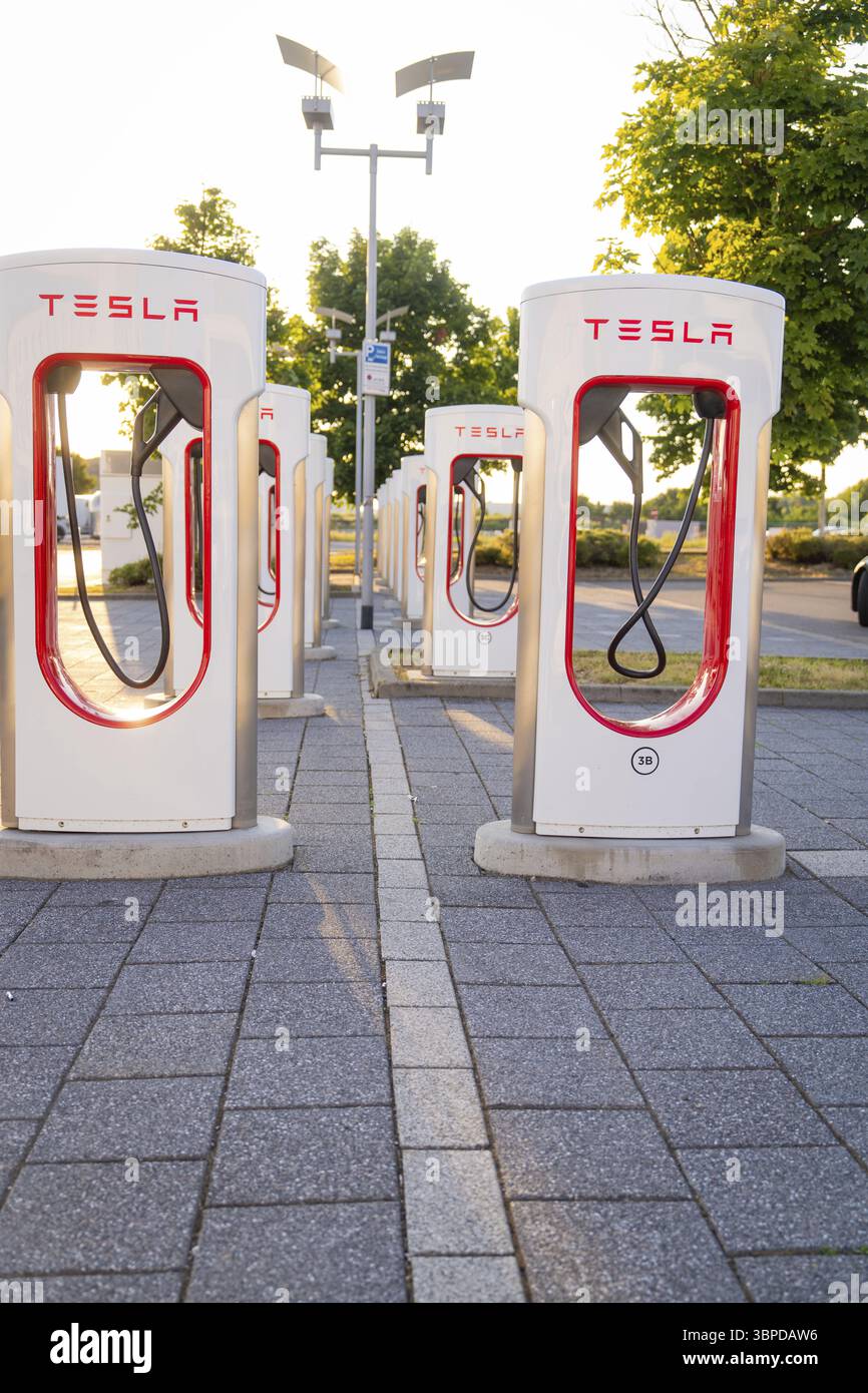 Mehrere Tesla Ladestationen in einer städtischen Umgebung mit Sonnenlicht und Bäumen, Tesla Supercharger Boeblingen, Deutschland, Europa Stockfoto