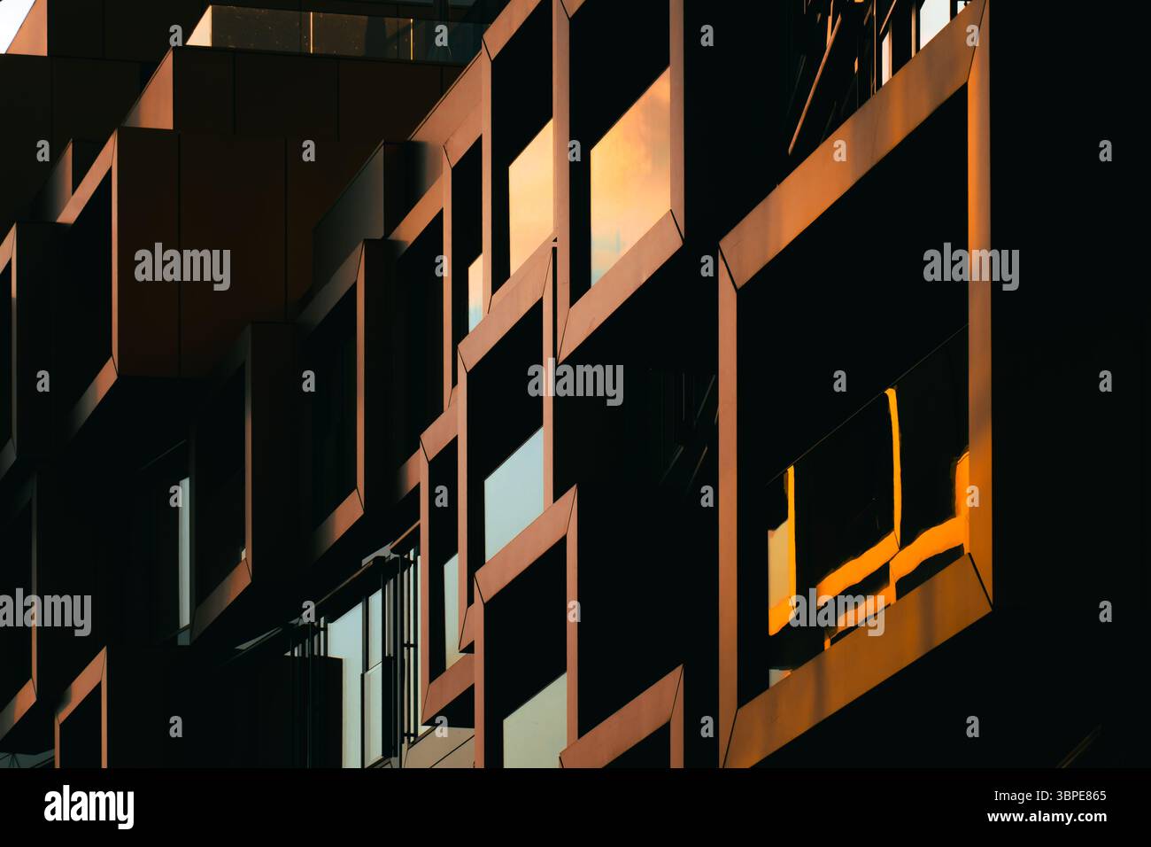 Moderne Wohnfassade mit gestapelten orangen Balkonen, die starke geometrische Schatten bilden Stockfoto