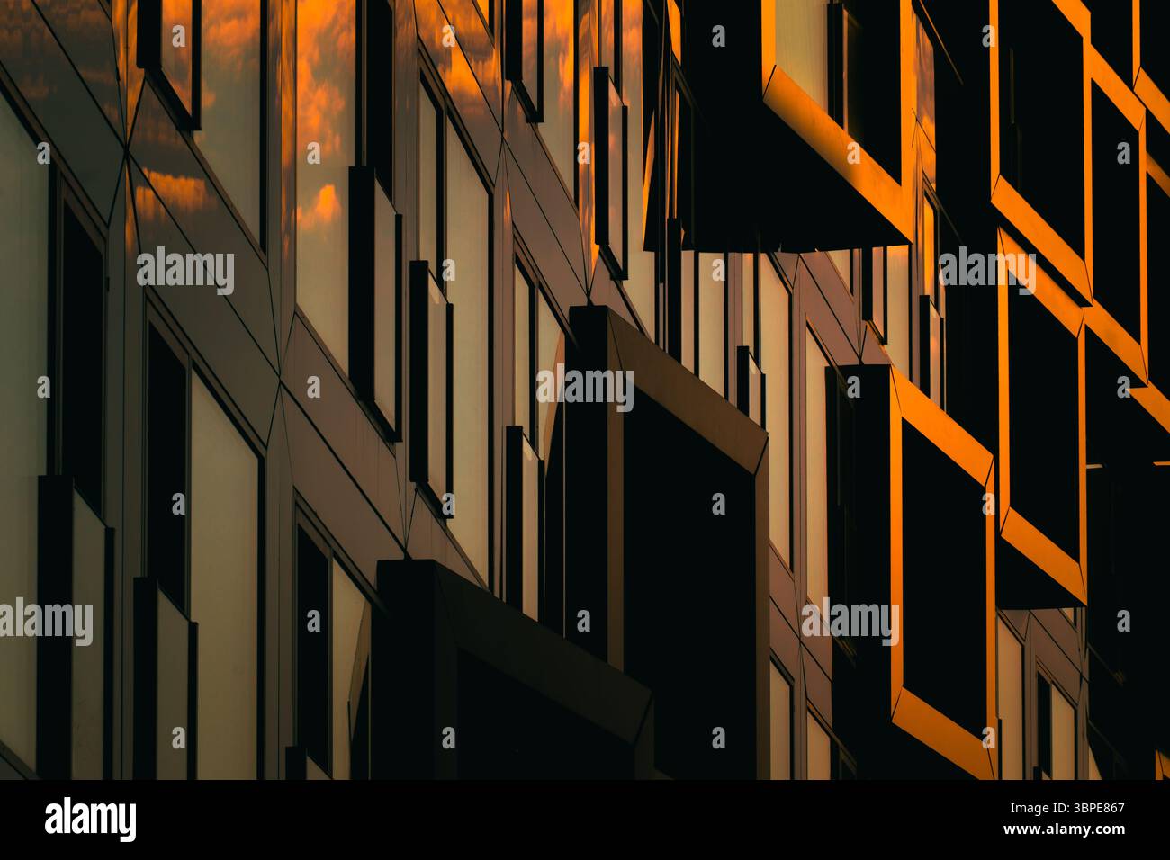 Moderne Wohnfassade mit gestapelten orangen Balkonen, die starke geometrische Schatten bilden Stockfoto