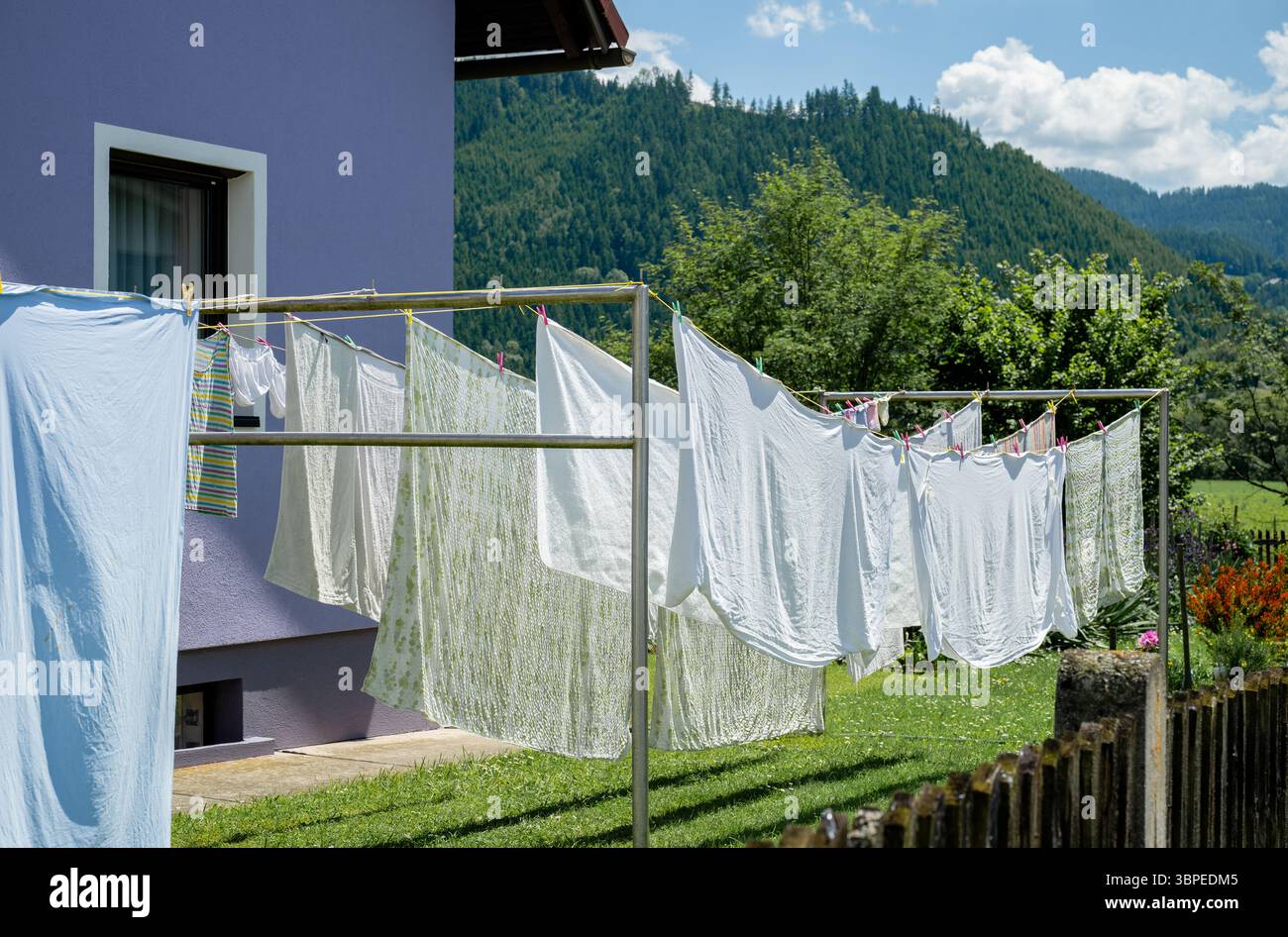 Frisch gewaschene Wäsche hängt am sonnigen Tag im Garten an der Wäscheleine Stockfoto