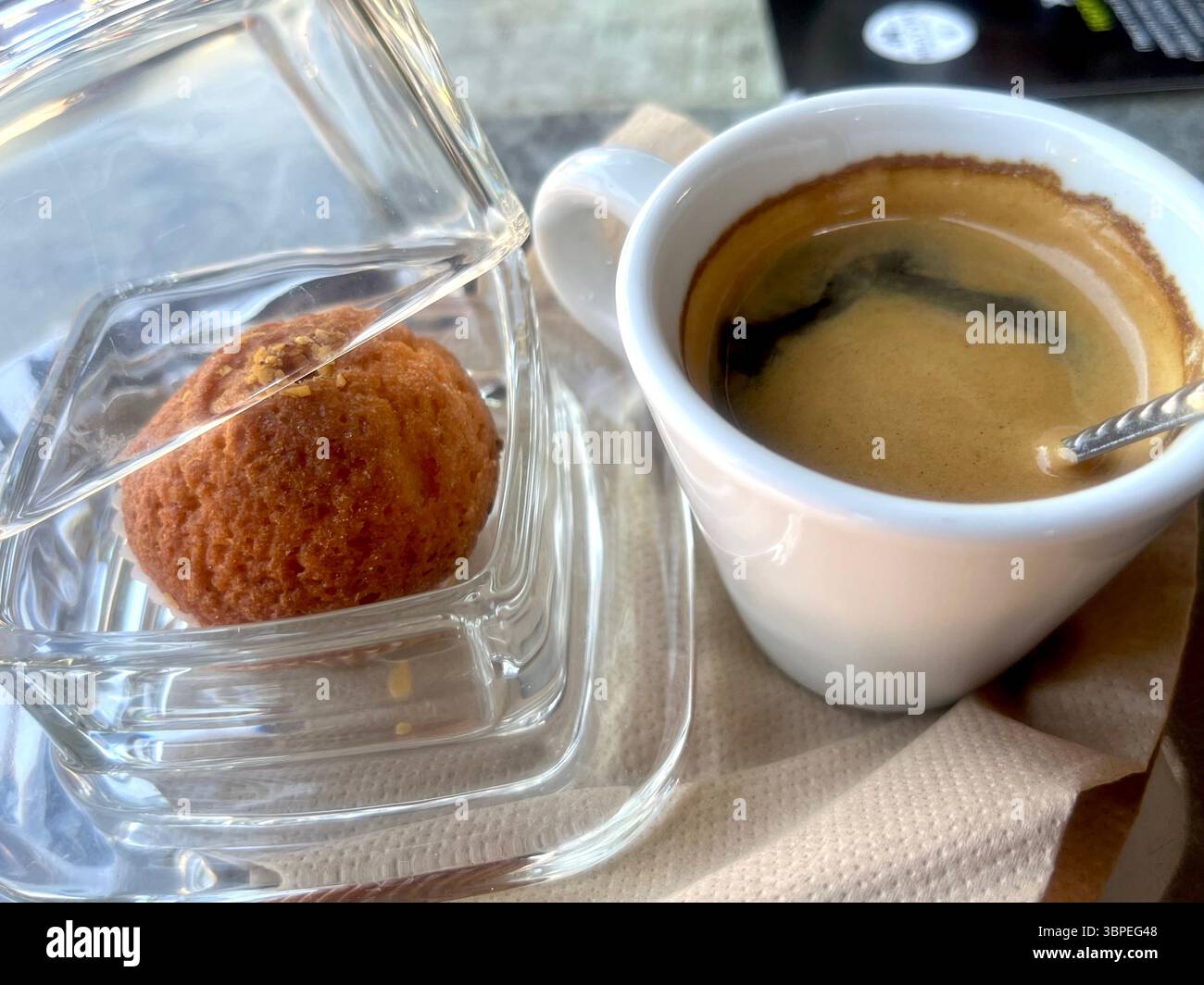 Eine Tasse Kaffee und ein kleiner Kuchen im Glas werden in einem Café oder Café serviert Stockfoto