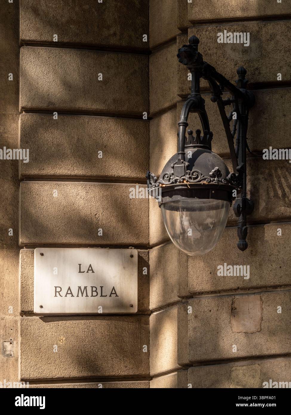 Ein klassisches Marmor-Straßenschild für „La Rambla“ unter einer kunstvollen, historischen schmiedeeisernen Lampe in einem Gebäude in Barcelona, Spanien. Stockfoto