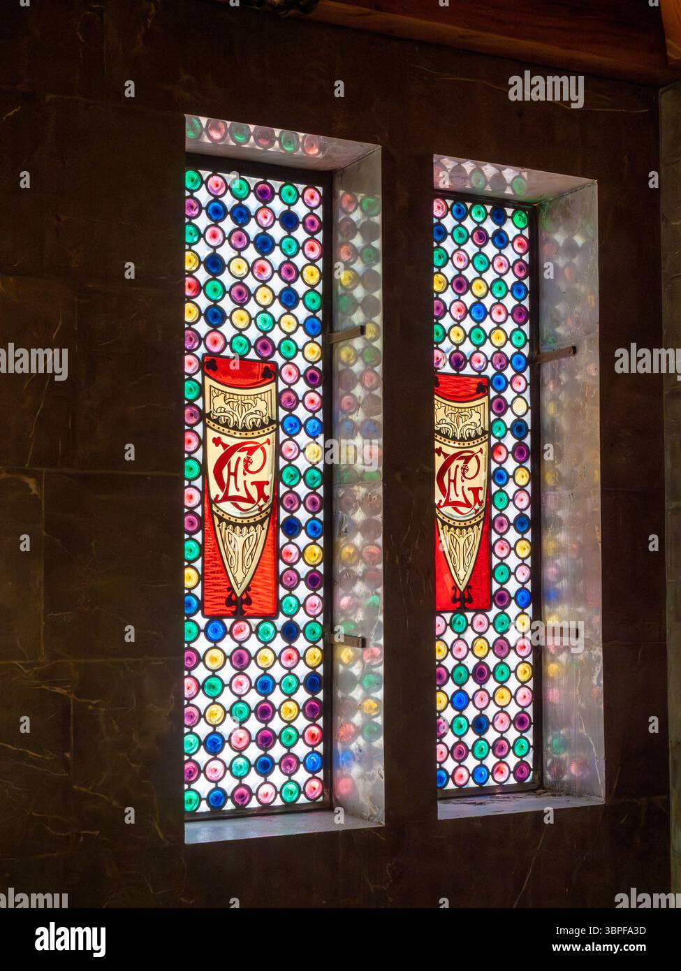 Detail eines Buntglasfensters mit den Initialen von Eusebi Güell in Antoni Gaudí Palau Güell Villa in Barcelona, Spanien. Stockfoto