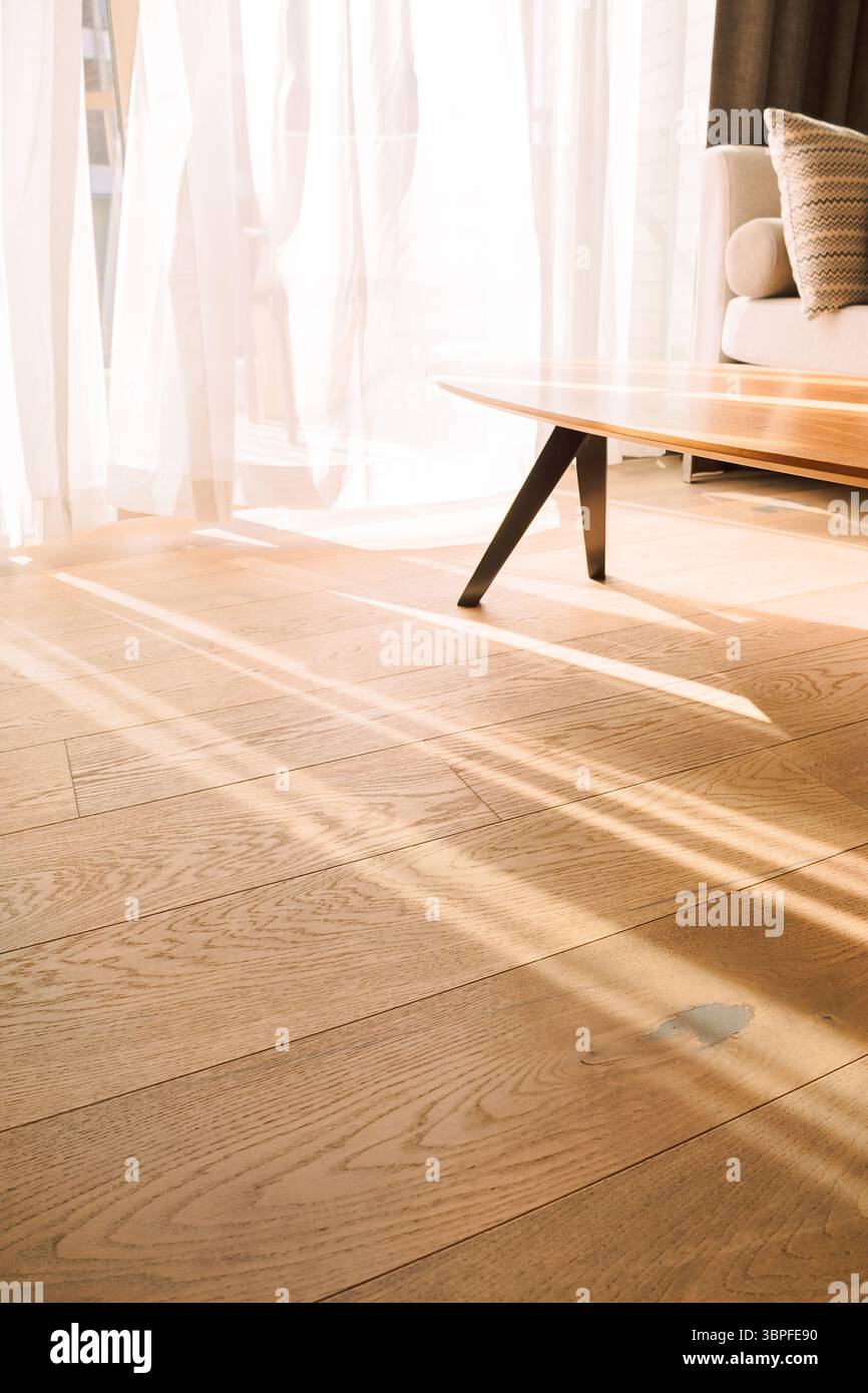 Moderne Zimmereinrichtung mit offenem Fenster in minimalem Stil. Transparenter Tüll mit morgendlichen Sonnenstrahlen auf Schattenhintergrund. Vertikales Foto. Stockfoto