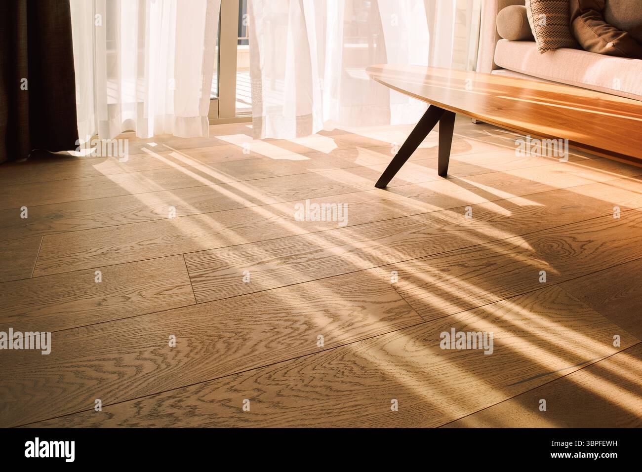 Moderne Innenausstattung mit offenem Fenster in minimalem Stil. Transparenter Tüll mit Morgensonnenstrahlen auf Schattenhintergrund Stockfoto