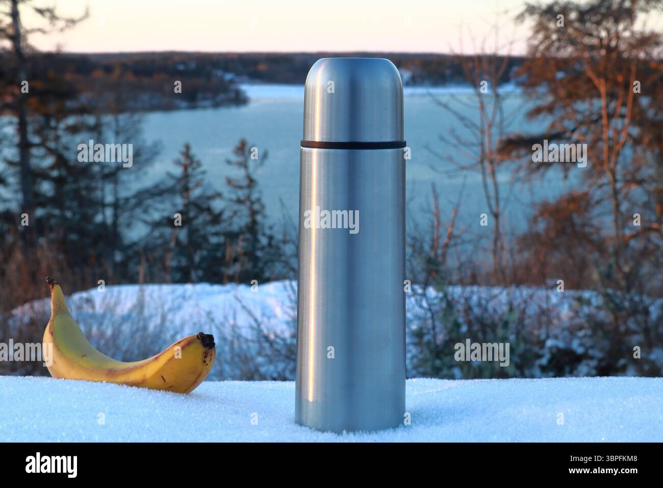Thermos und Banane in einer verschneiten Winterlandschaft. See im Hintergrund. Nahaufnahme und isoliert. Stockholm, Schweden, Europa. Stockfoto