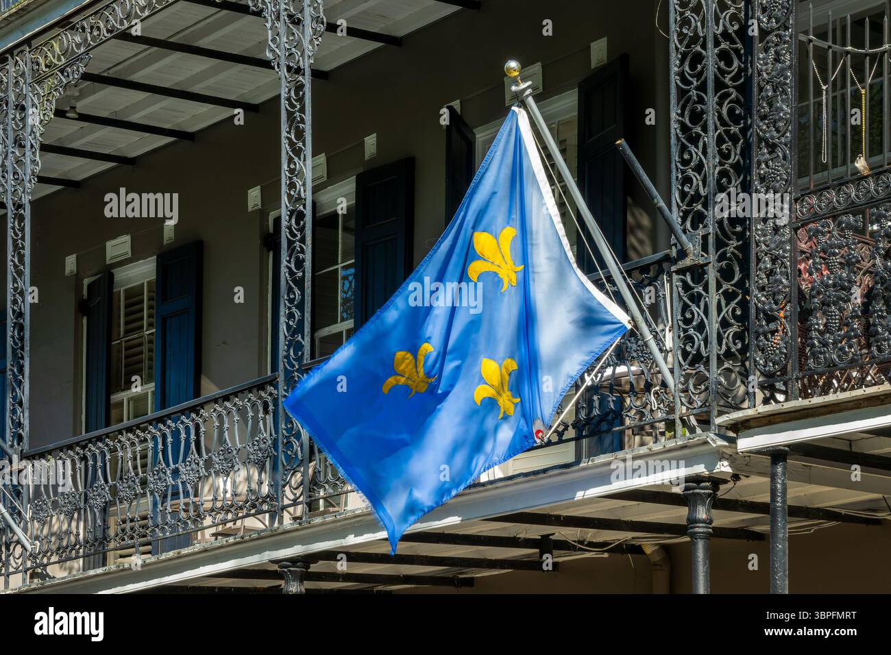 NOLA-Flagge mit goldenem Fleur-de-Lis und Architektur mit Balkonen und Säulen mit Schmiedearbeiten im French Quarter, New Orleans, Louisiana Stockfoto
