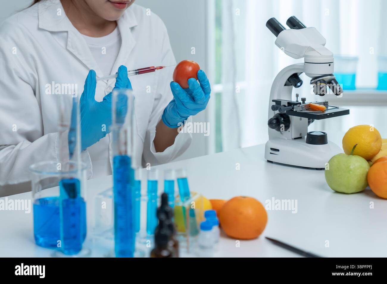 Wissenschaftler überprüfen chemische Lebensmittelrückstände im Labor. Kontrollexperten prüfen die Qualität von Früchten, Wissenschaftler injizieren Chemikalien in Äpfel für Experimente Stockfoto
