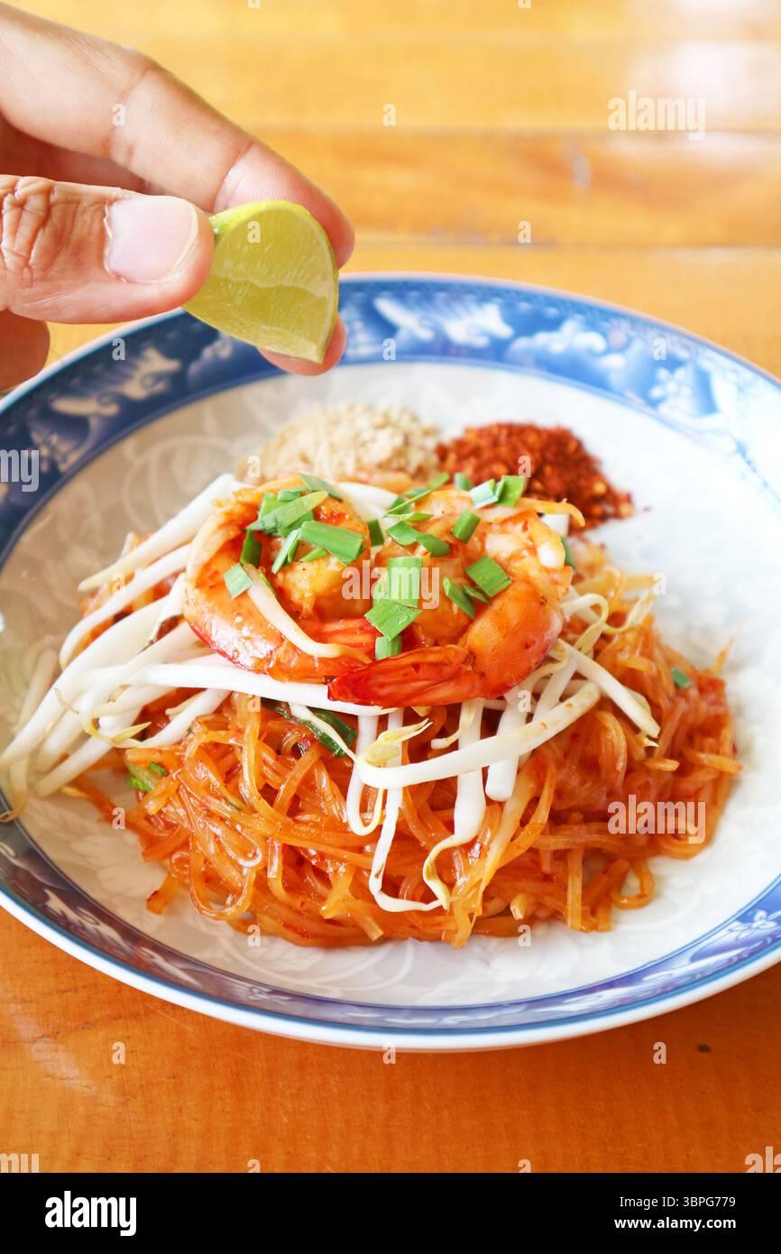 Drücken Sie Limettensaft in frisch gekochte Pad Thai Noodle, um die Schärfe zu erhöhen Stockfoto