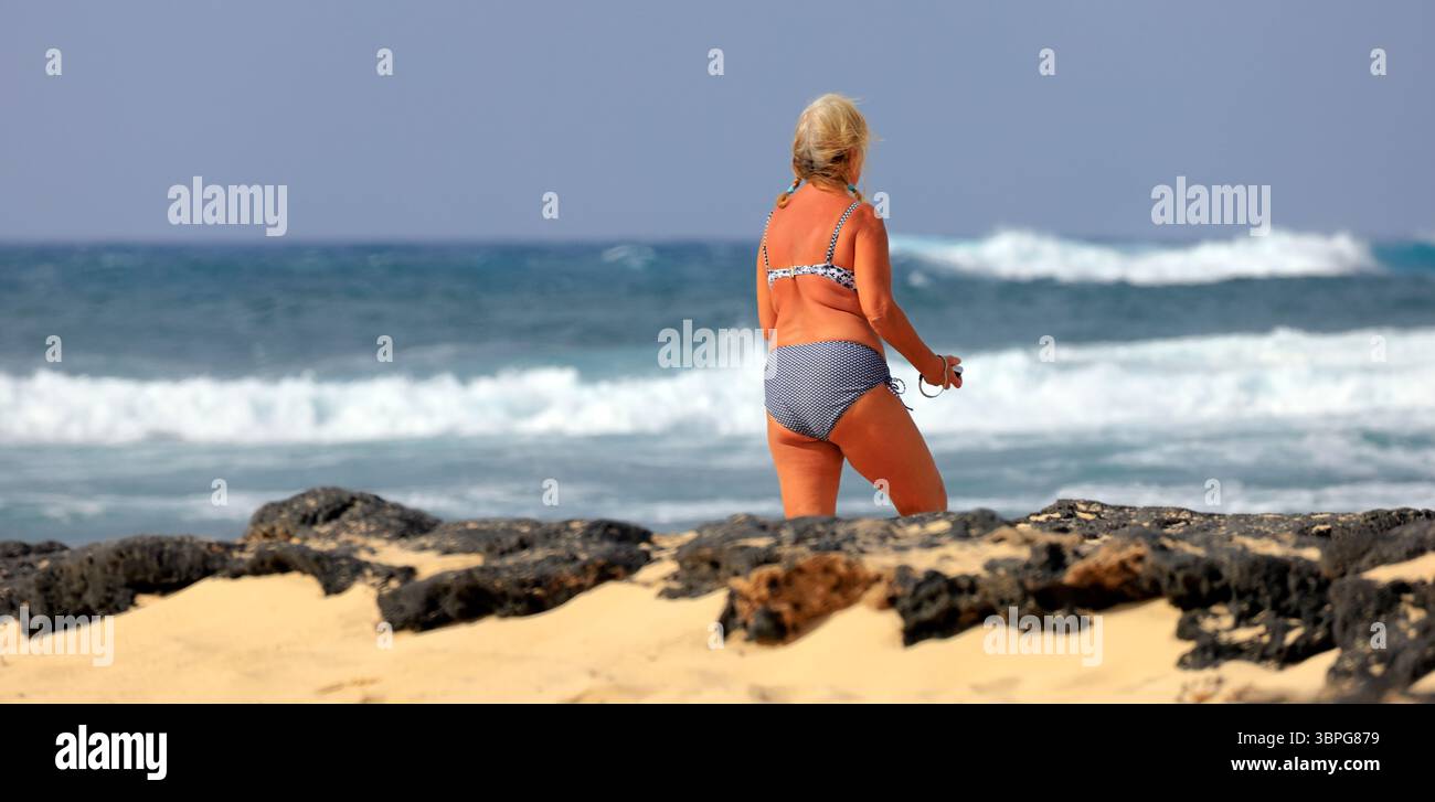 Frau im Badeanzug, die an der Atlantikküste in El Cotillo, Fuerteventura, den Kanarischen Inseln, Spanien, Europa, EU. Aufgenommen 2025 Stockfoto