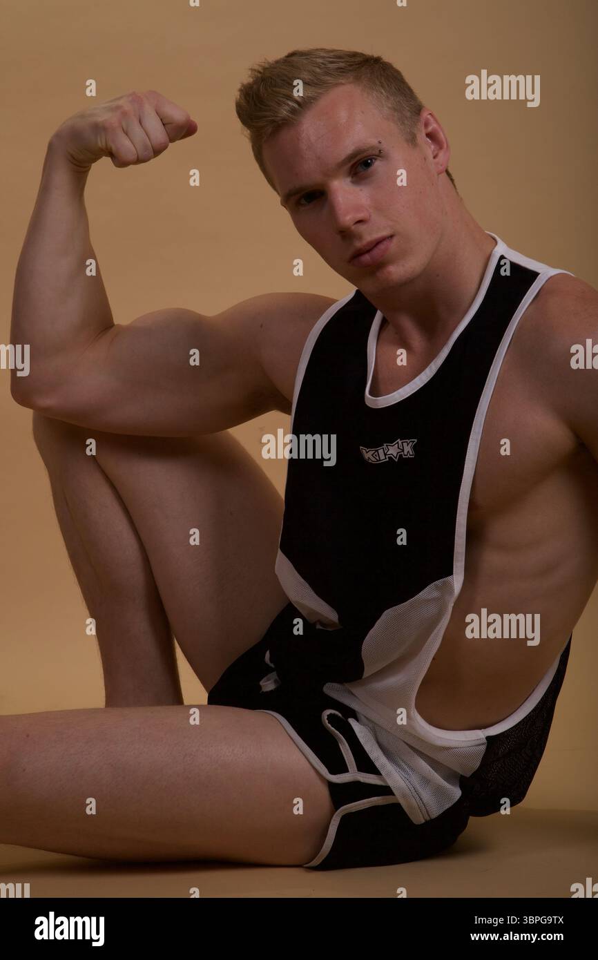 Ein muskulöses männliches Model, das ein schwarz-weißes KIK-Tanktop mit Shorts trägt Stockfoto