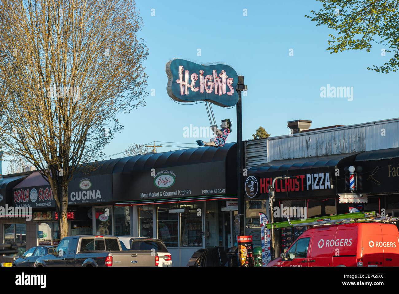 Straßenblick auf Burnaby Heights in British Columbia, zeigt lokale Unternehmen und das berühmte Neonschild „Heights“ über den Geschäften. Stockfoto