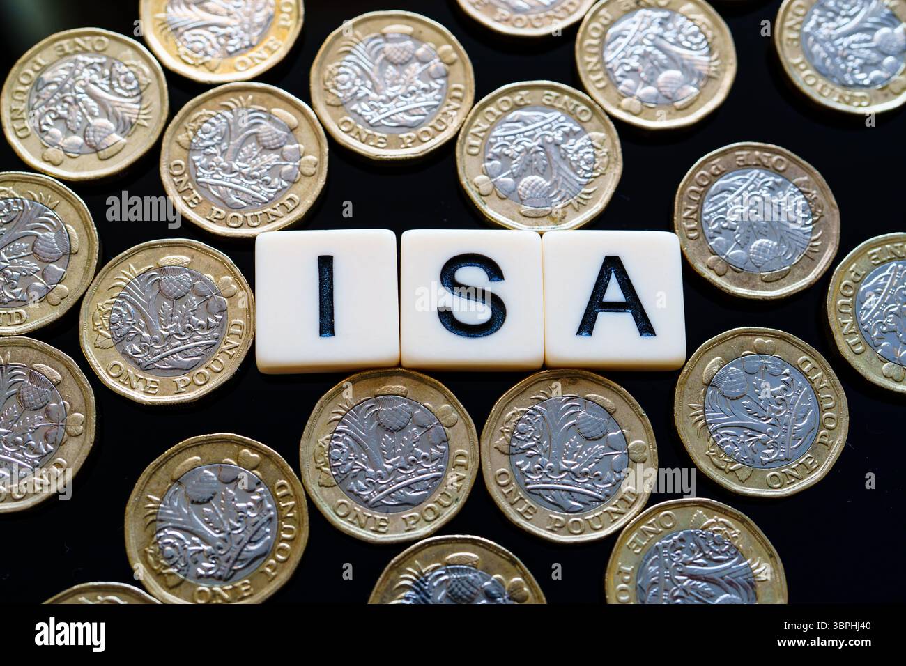Individuelles Sparkonto. Flache ISA-Buchstabensteine, die von mehreren britischen Pfund-Münzen umgeben sind, bedeuten steuereffiziente persönliche Einsparungen im Vereinigten Königreich. Stockfoto
