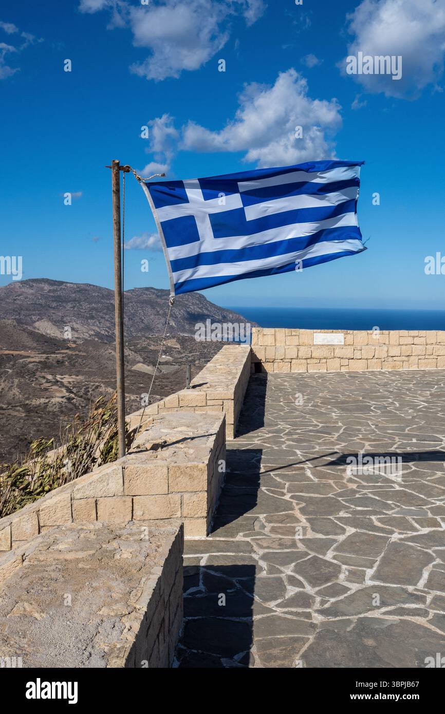 Griechische Flagge winkt im Wind auf einem Aussichtspunkt mit Blick auf die Berge und das Meer auf kreta, griechenland Stockfoto