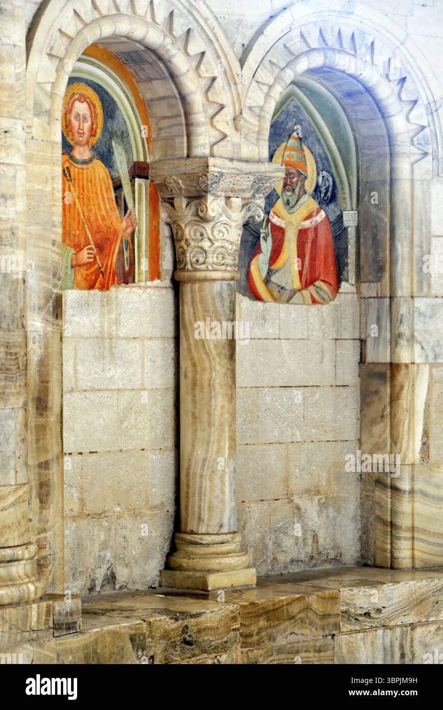 Zwei farbenfrohe Fresken von Heiligen, eingebettet in eine alte Mauer mit reich verzierten Säulen, Abteikirche Abbazia di Sant'Antimo, nahe Montalcino, pro Stockfoto