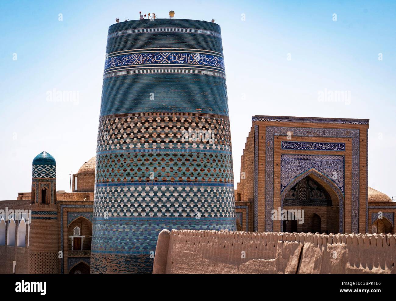 Ein atemberaubender Blick auf die alte Architektur in Chiwa, Usbekistan, mit einem hohen, aufwendig gestalteten Minarett und einem historischen Gebäude mit Farbtönen Stockfoto