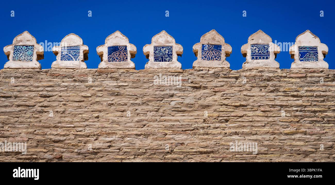 Eine Steinmauer mit dekorativen blauen und weißen Fliesen vor einem klaren blauen Himmel. Die Fliesen sind mit komplizierten Mustern und Designs versehen, die eine kulturelle Note verleihen Stockfoto