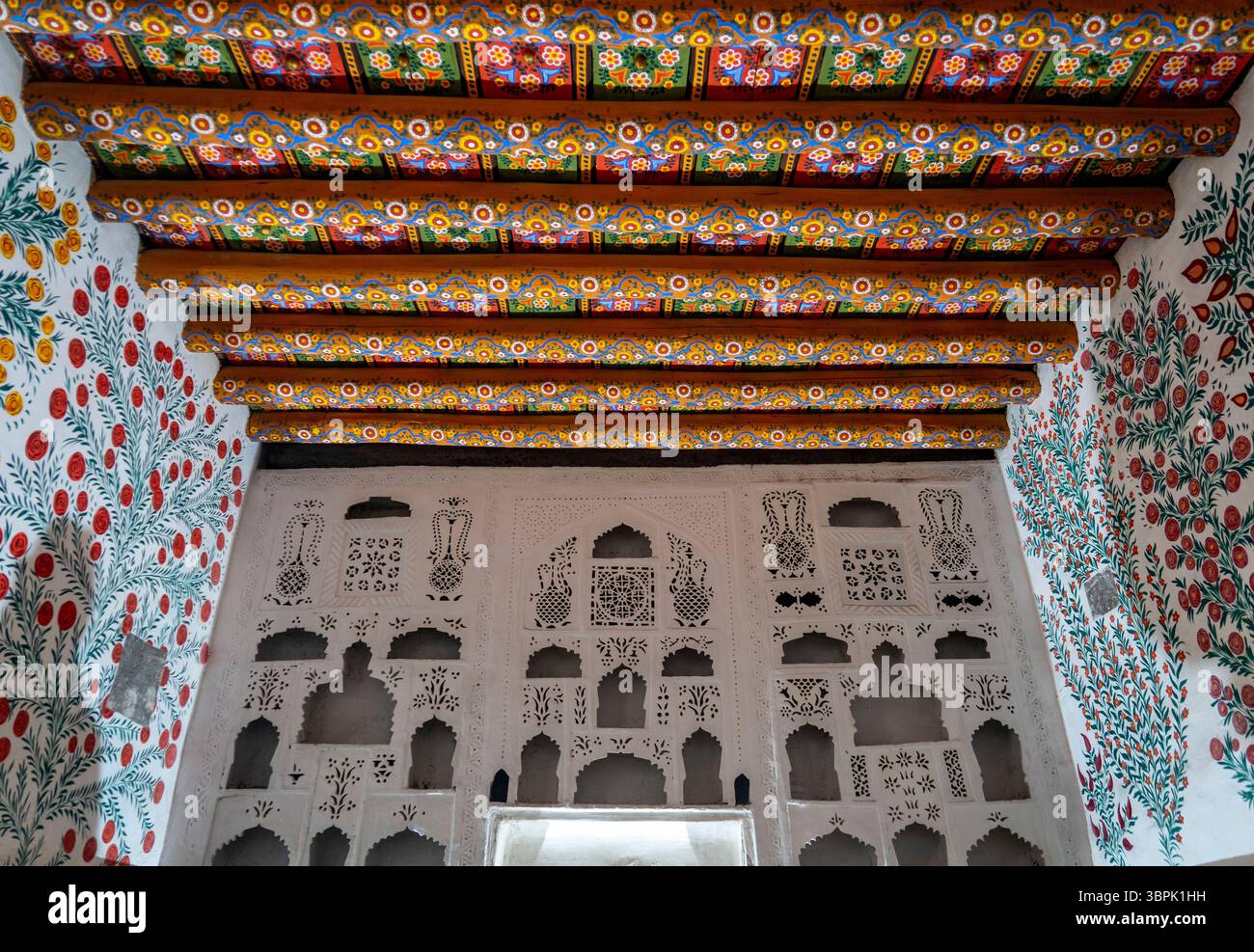 Ein wunderschön dekoriertes Interieur mit aufwändig bemalten Holzbalken und lebhaften Blumenmustern an den Wänden. Das Design ist traditionell Stockfoto