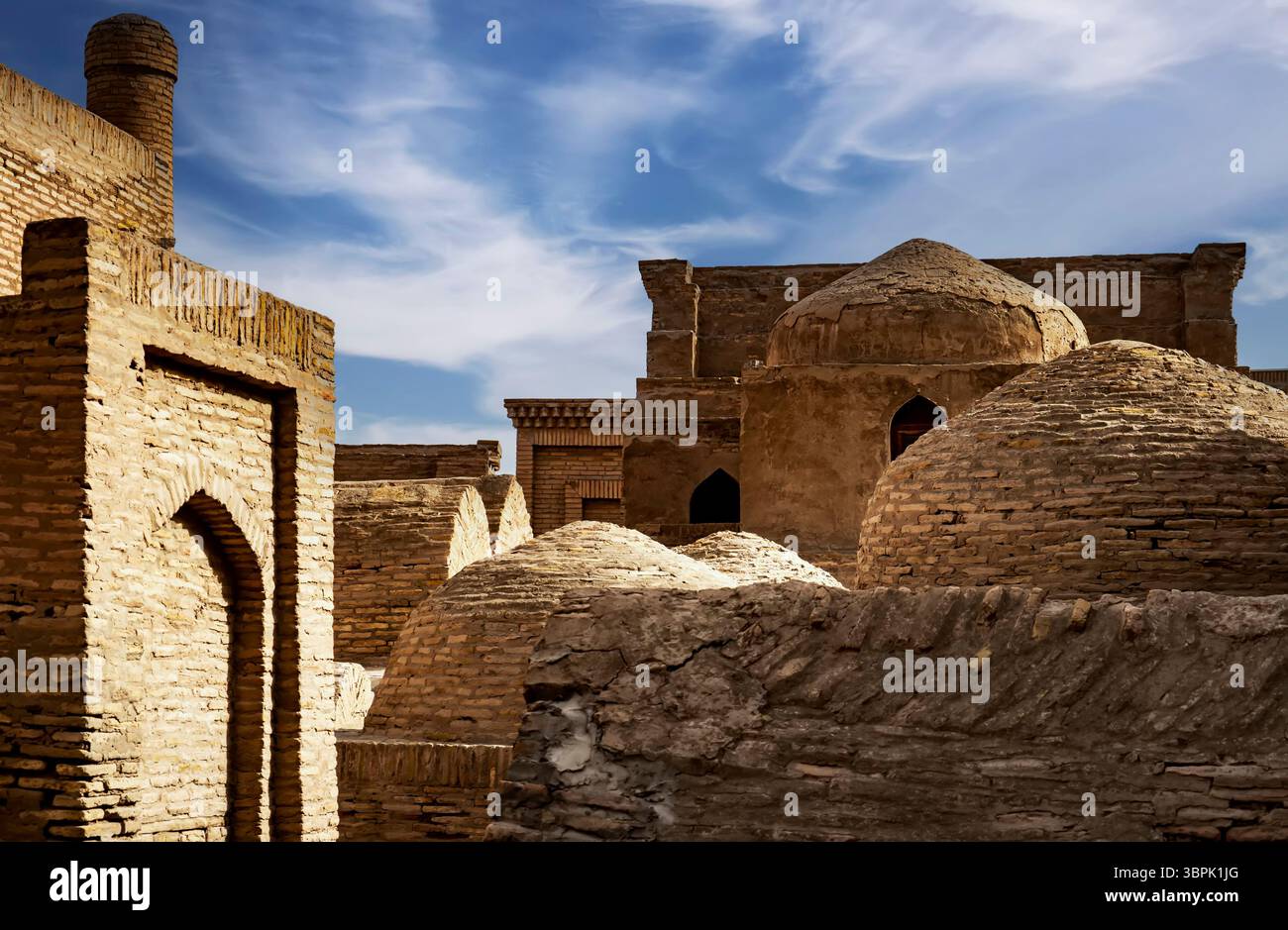 Ein malerischer Blick auf die alte Backsteinarchitektur mit Kuppelbauten unter einem blauen Himmel mit schimmernden Wolken. Das Bild erfasst die historische Essenz o Stockfoto