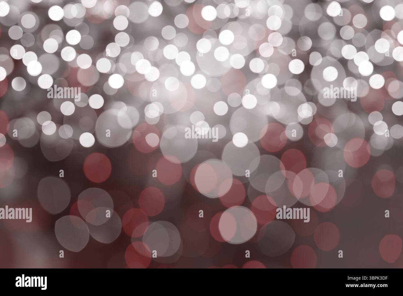 Das flache Bokeh-Lichtmuster verteilt weiche weiße und gedämpfte rote Kreise über einen unscharfen Hintergrund Stockfoto