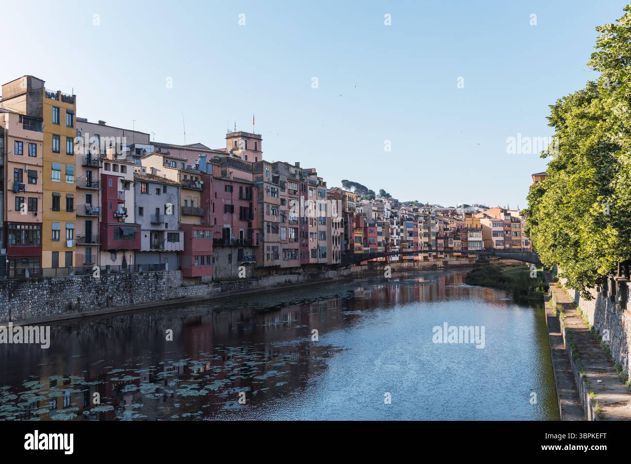 Der onyar River fließt friedlich durch girona und spiegelt die lebhaften Farben der Häuser am Ufer wider, wodurch eine malerische Szene im Katalon entsteht Stockfoto
