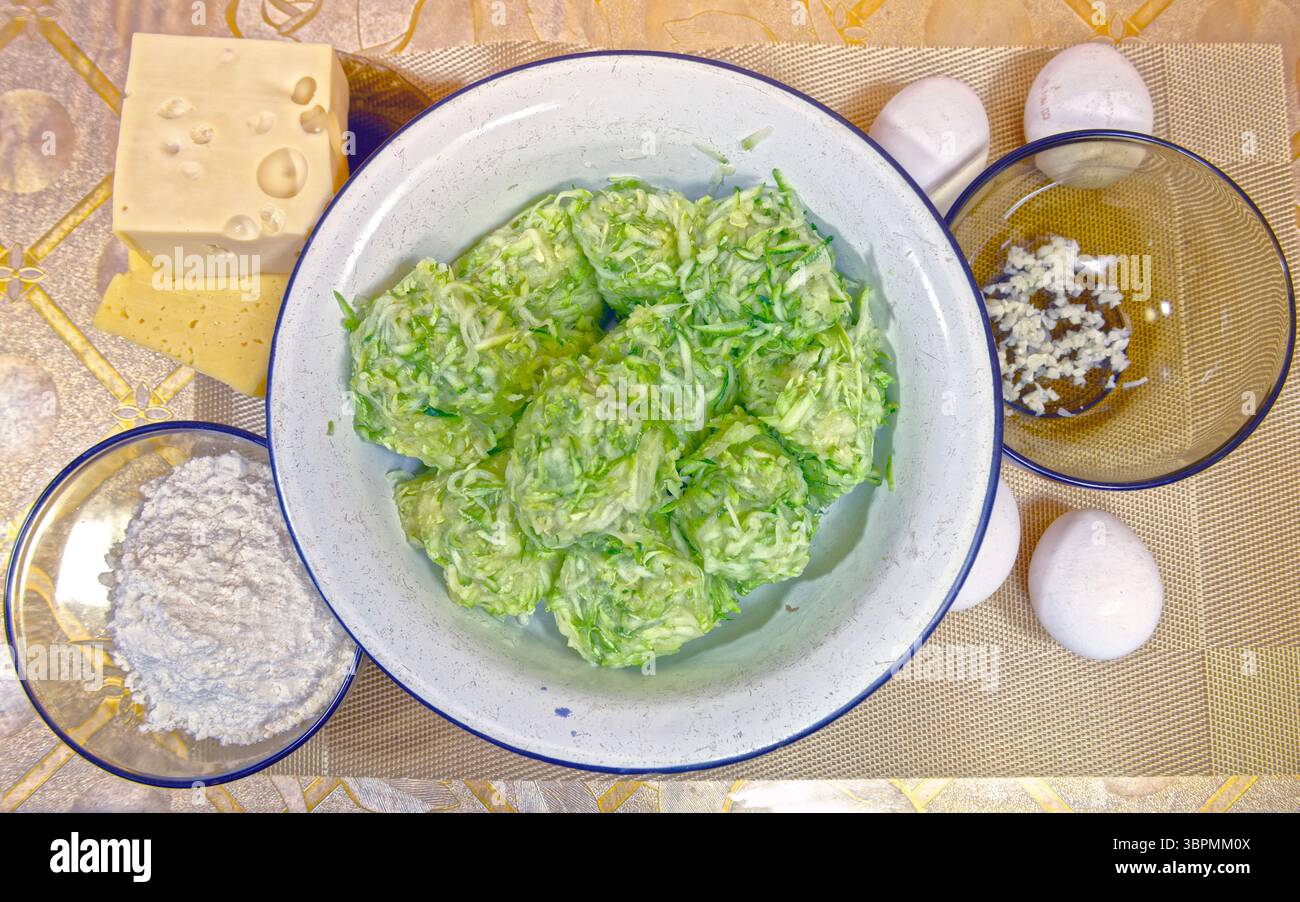 Nahaufnahme von oben auf den ersten Schritt des Zucchini-Auflaufs mit allen Zutaten auf dem Tisch. Stockfoto