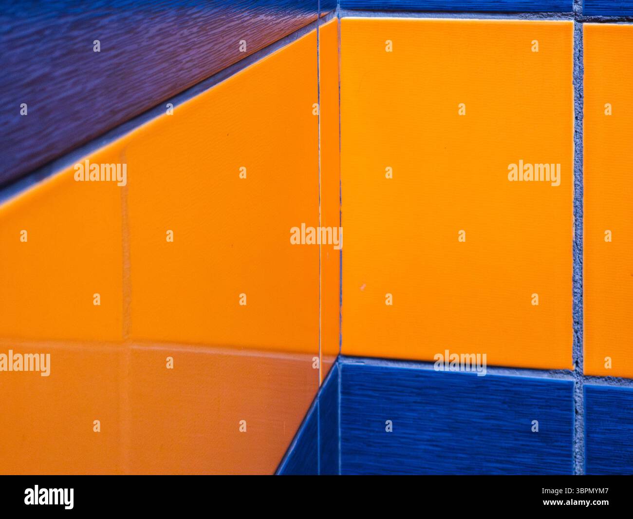 Hellblaue und orangene Fliesen kreuzen sich und zeigen ihre lebendigen Farben. Die klaren Linien und die glänzende Oberfläche unterstreichen die moderne Ästhetik in diesem stilvollen Stil Stockfoto