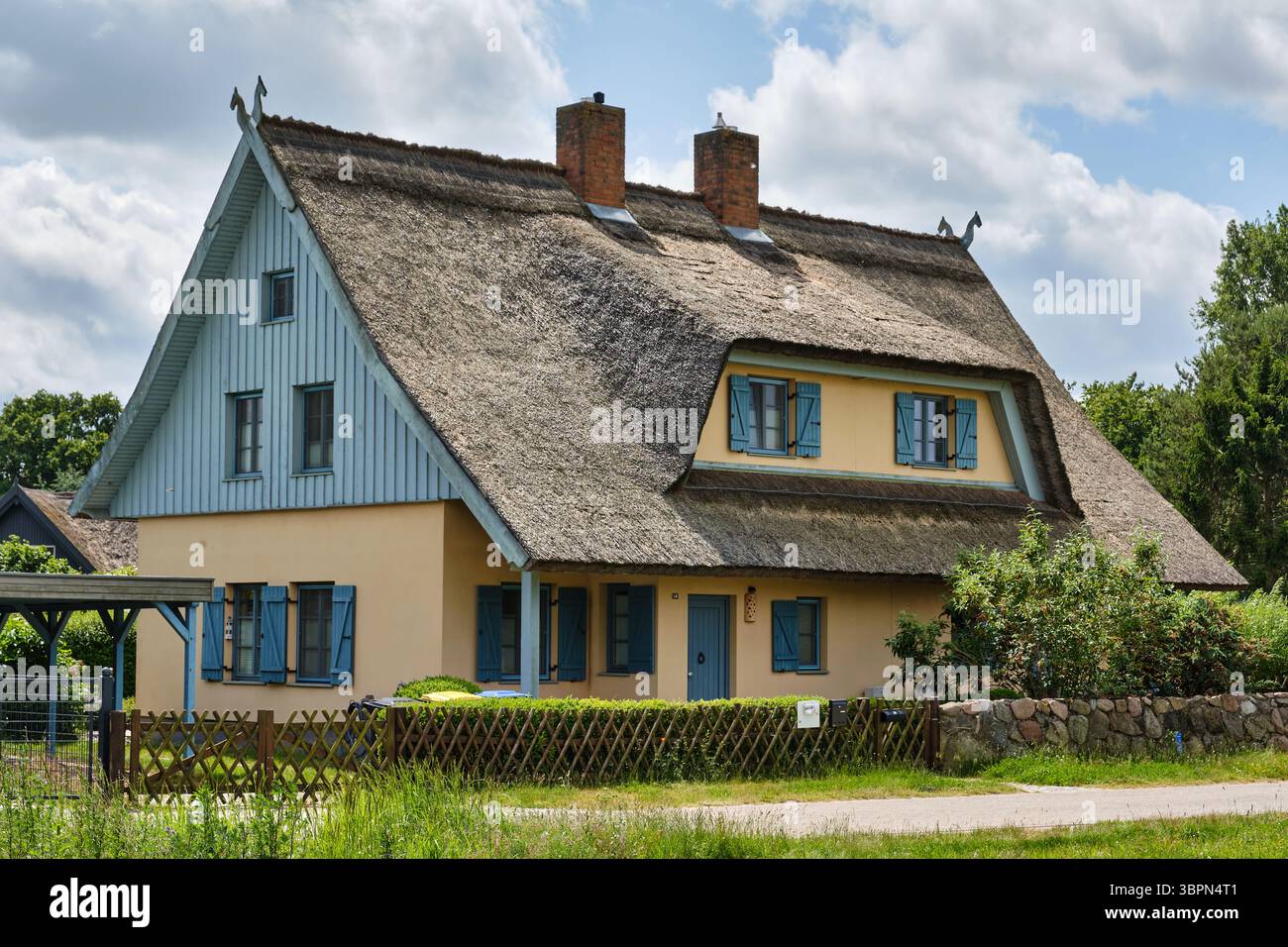 16. Juni 2025 - Kamminke-Deutschland: Traditionelles strohgedecktes Ferienhaus im norddeutschen Stil mit moosbedecktem Dach und farbenfroher Fassade, umgeben von gr Stockfoto