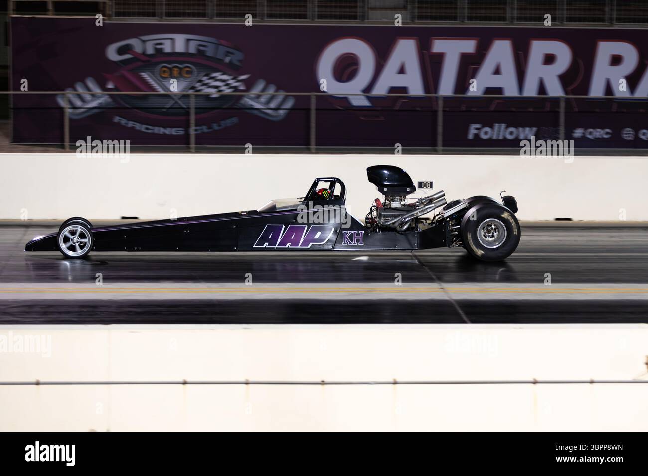 Motion Blur Drag Racing bei Nacht, bei dem Autos auf der Rennstrecke mit Zuschauern in der Nähe konkurrieren Stockfoto
