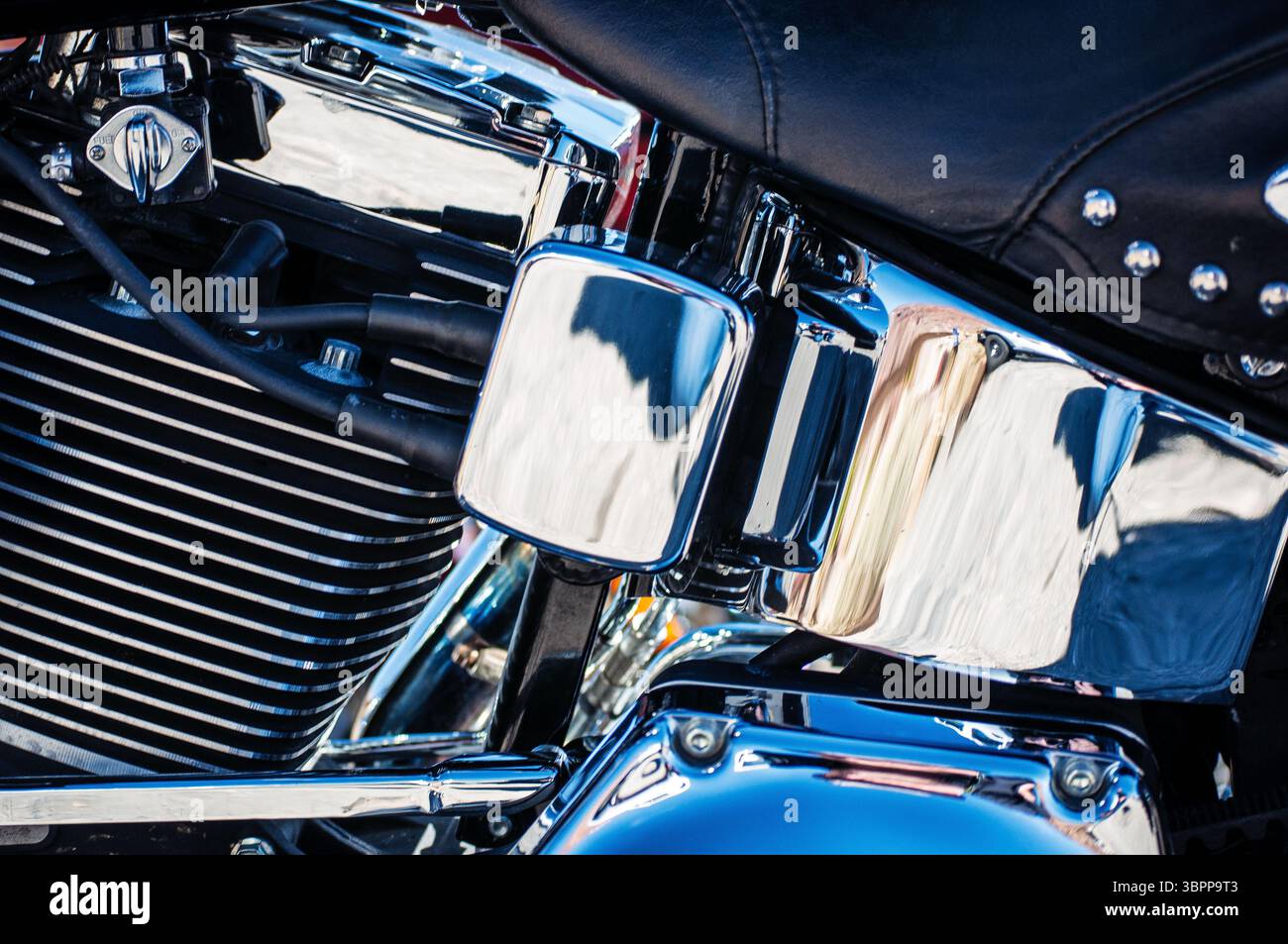In einer detaillierten Nahaufnahme werden die Motorabdeckungen, Kühlrippen und die Ledersitze eines Motorrads in glänzendem Chrom erfasst. Stockfoto