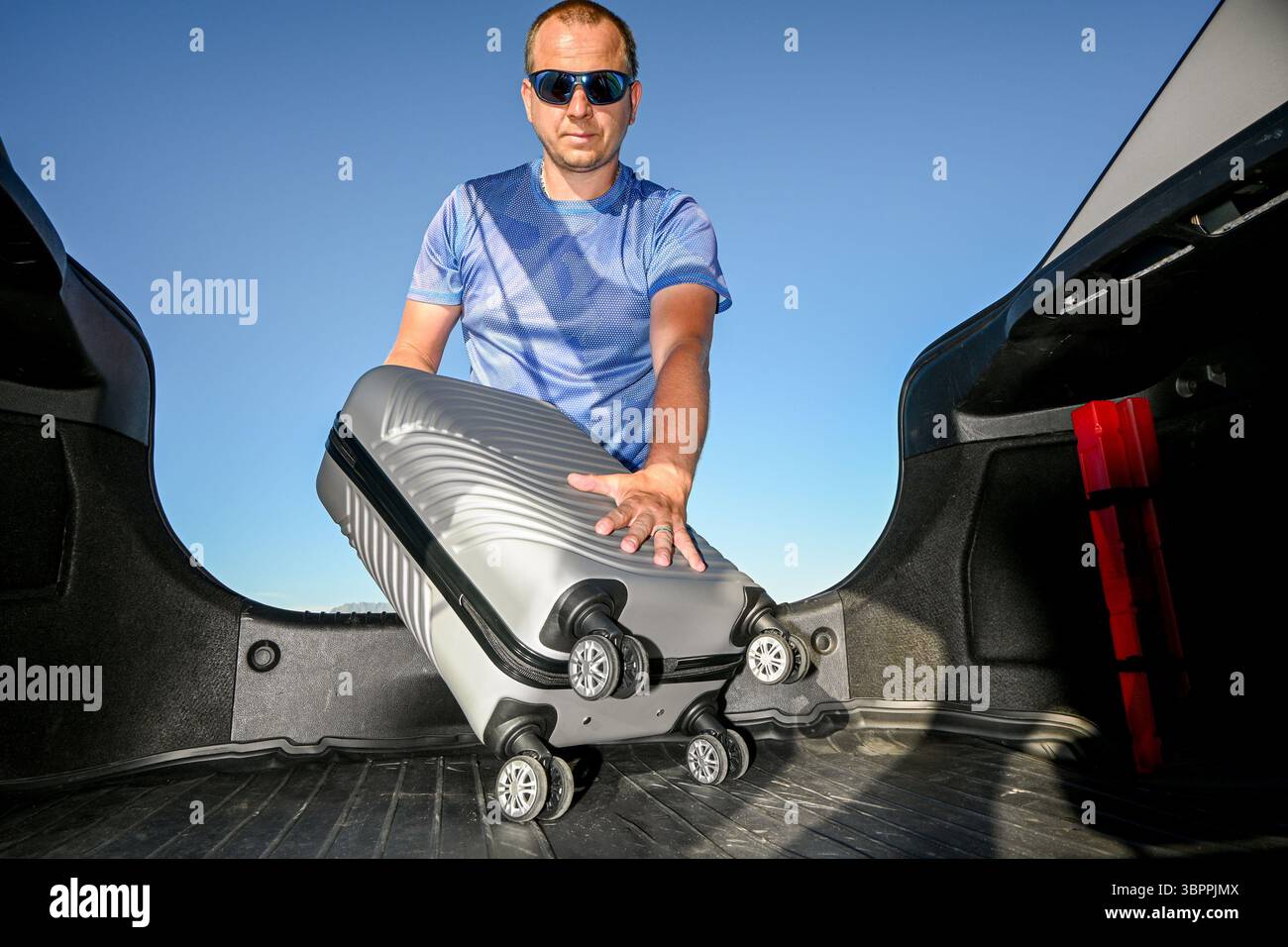 Mann, der Gepäck in den Kofferraum lädt und sich auf ein Abenteuer vorbereitet. Stockfoto
